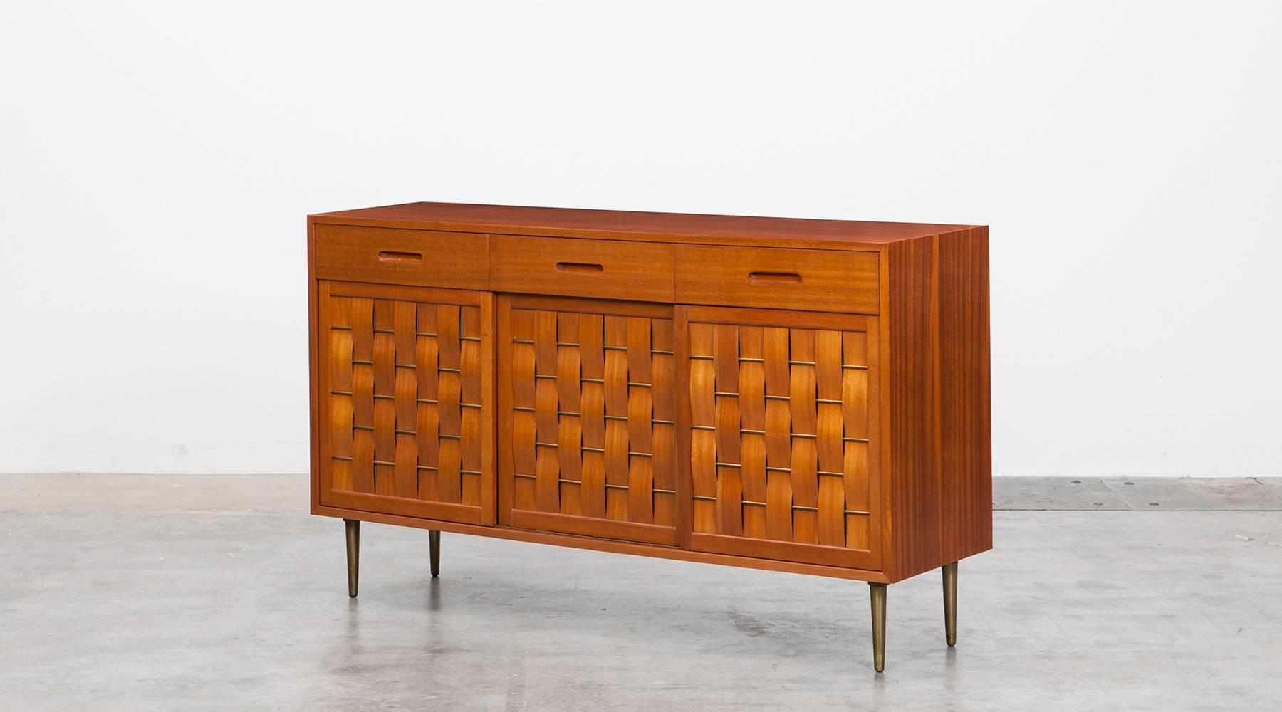 Very rare Edward Wormley sideboard comes in mahogany and a very high quality finish. Three-door credenza comes with mahogany case with brass details on doors and legs. Three woven bleached rosewood sliding doors. Manufactured by Dunbar.

US-designer