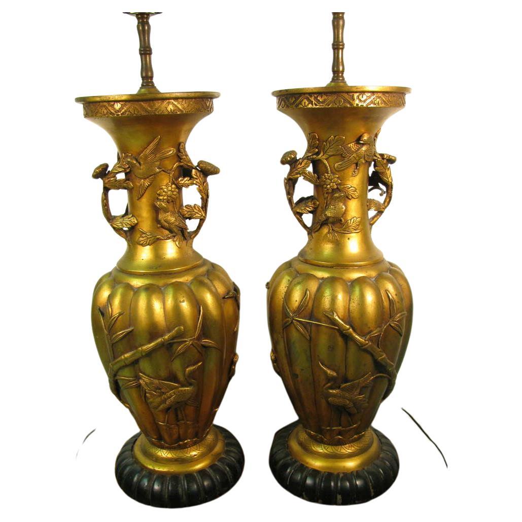 Amazing pair of gilt Chinese urns. Hand chased full bodied birds with floral leaves and bamboo. Scalloped wood base. In excellent vintage condition with minimal wear, totally elegant lamps.