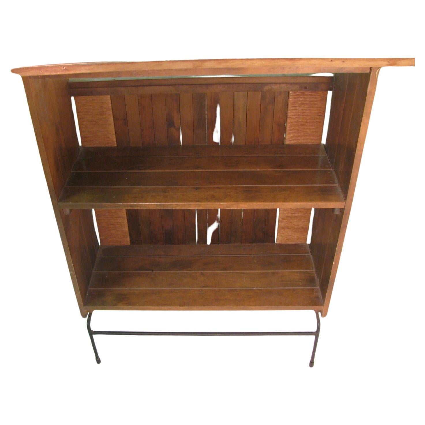 Fabulous dry bar with maple slats and raffia paper apron on the sides and a iron footrest. Top is a laminate that looks like wood in great condition original to the piece. Two storage shelves in the back of the bar. In excellent vintage condition