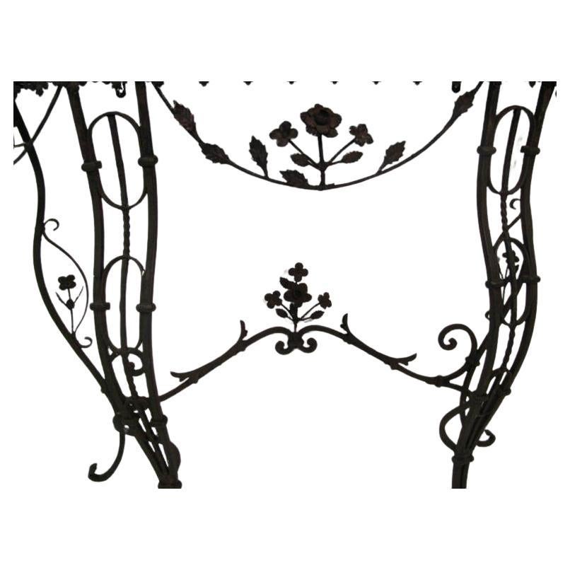 Fabulous elegant hand wrought iron base with delicate detailing including ringlets, flowers and leaves. Hammered metal fleur de leis border along with serpentine legs. In original condition. Marble recently polished. Pair it with your mirror or with