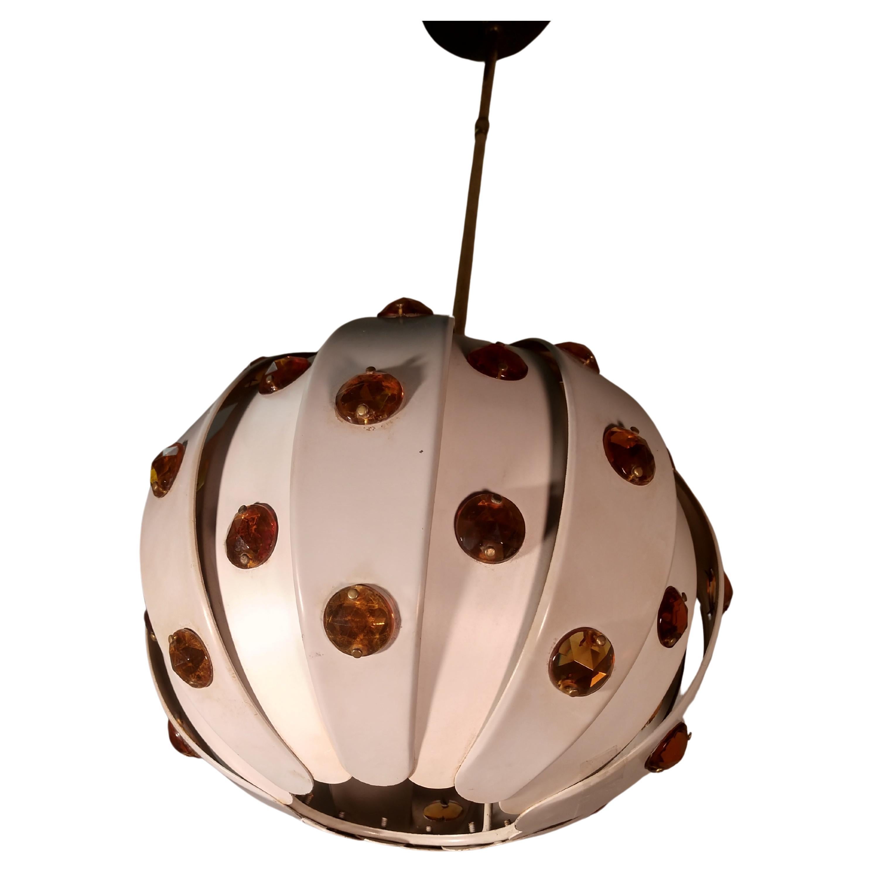 Fabulous jeweled pendant lamp which when lit illuminates the plastic Amber colored jewels. Organically styled,
with enameled metal panels imitating leaves. Adjustable down rod is brass along with ceiling canopy. In excellent vintage condition with