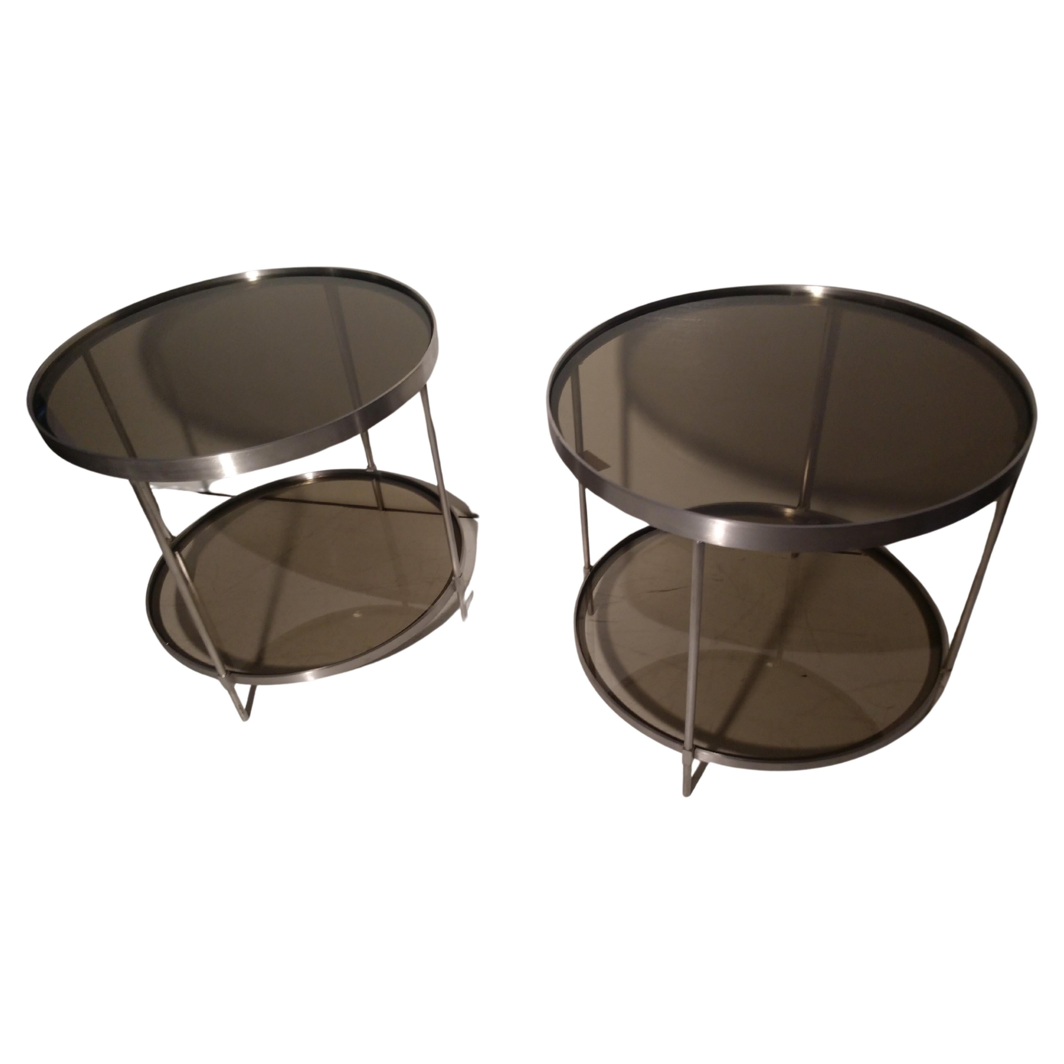 Fabulous pair of stainless steel tables with smoked glass top and bottom shelf. Tables are large 24in. diameter so they can be used as a cocktail table in a smaller setting by themselves, or together if the space works.
In excellent vintage