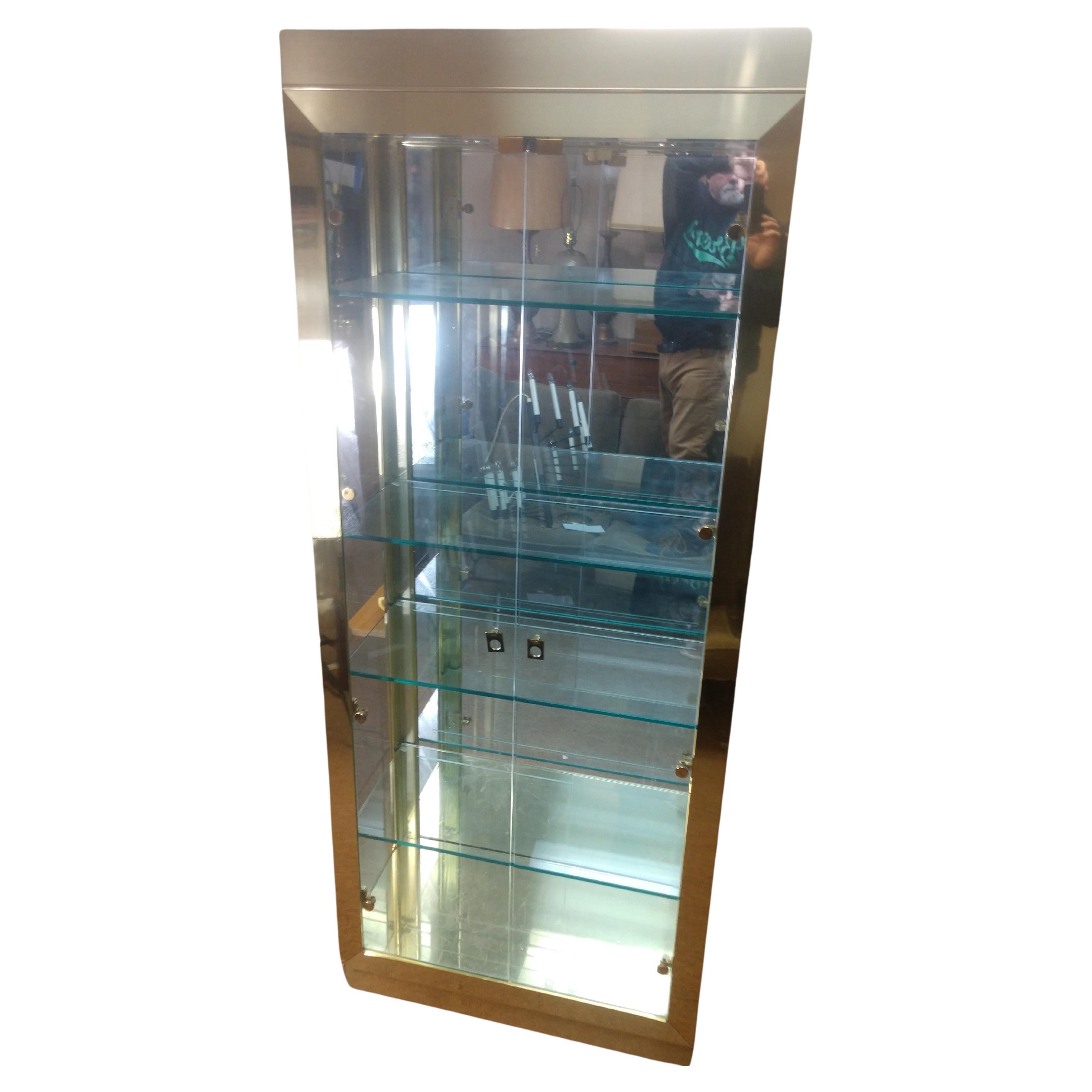 Fabulous brass and glass tall showcase with 4 thick glass shelves etched for showing plates. Shelves are adjustable. Two glass doors each hung on 4 hinges. In near perfect condition the exception being a corner on bottom left which has a minor