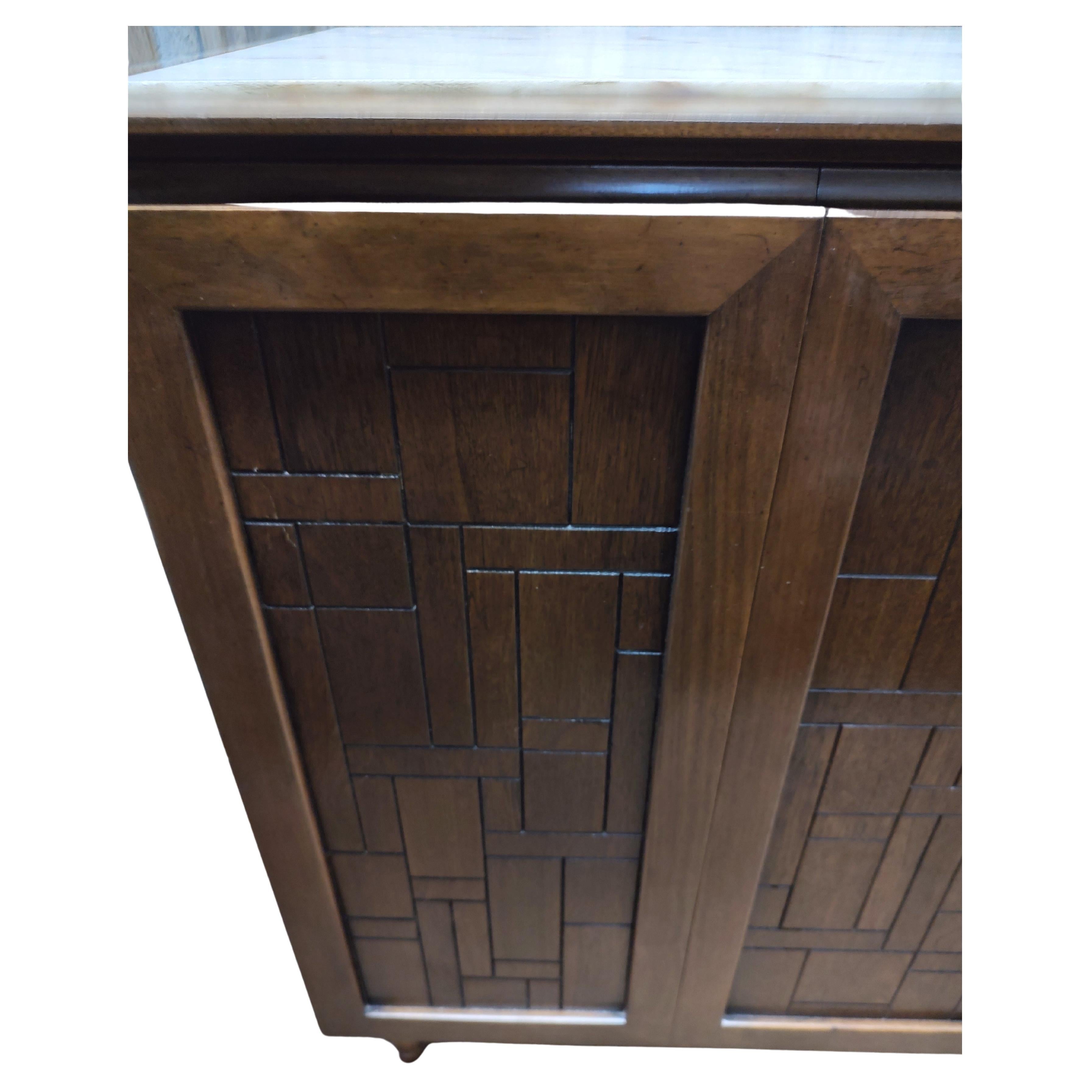 Fabulous brutalist credenza or long dresser by Bert England for John Stuart. Bi fold doors open to reveal 8 total drawers and a shelf. Walnut mosaic panels which are framed. Marble top on 90 % front edge is walnut. Brass tubular base with walnut