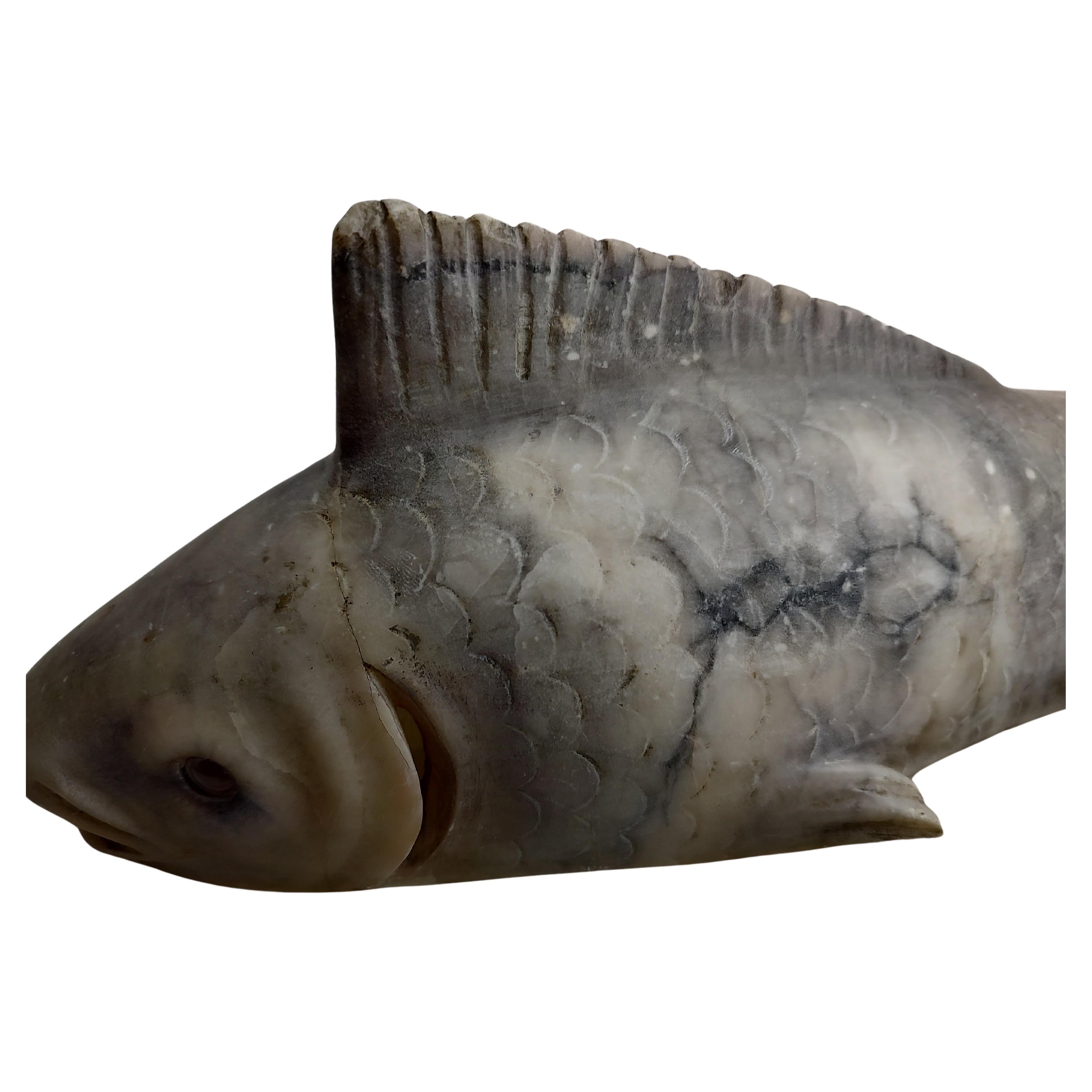 Fabulous fish night light table lamp. Carved from alabaster in two pieces. Fish sits in a carved cradle type form and secures it. Inline switch and when lit fishes eyes sparkle red. Base was professionally repaired. In excellent vintage condition