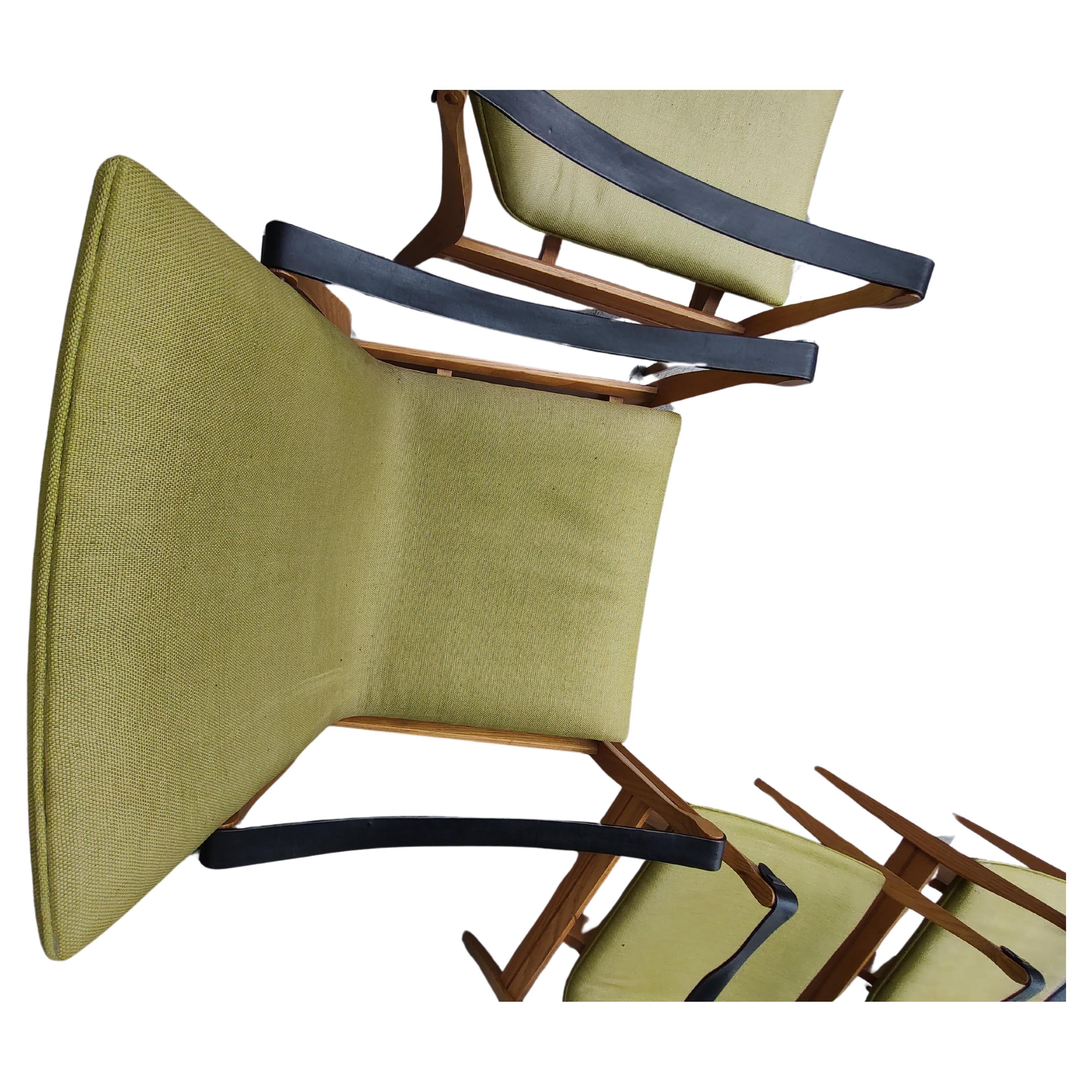Fabuleuse paire de chaises Safari par Karen et Ebbe Clemmensen pour Fritz Hansen. Montures en frêne avec lanières en cuir noir. Le tissu vert est bon et solide, sans dommage, mais un peu décoloré par le soleil. Les accents en laiton qui fixent les