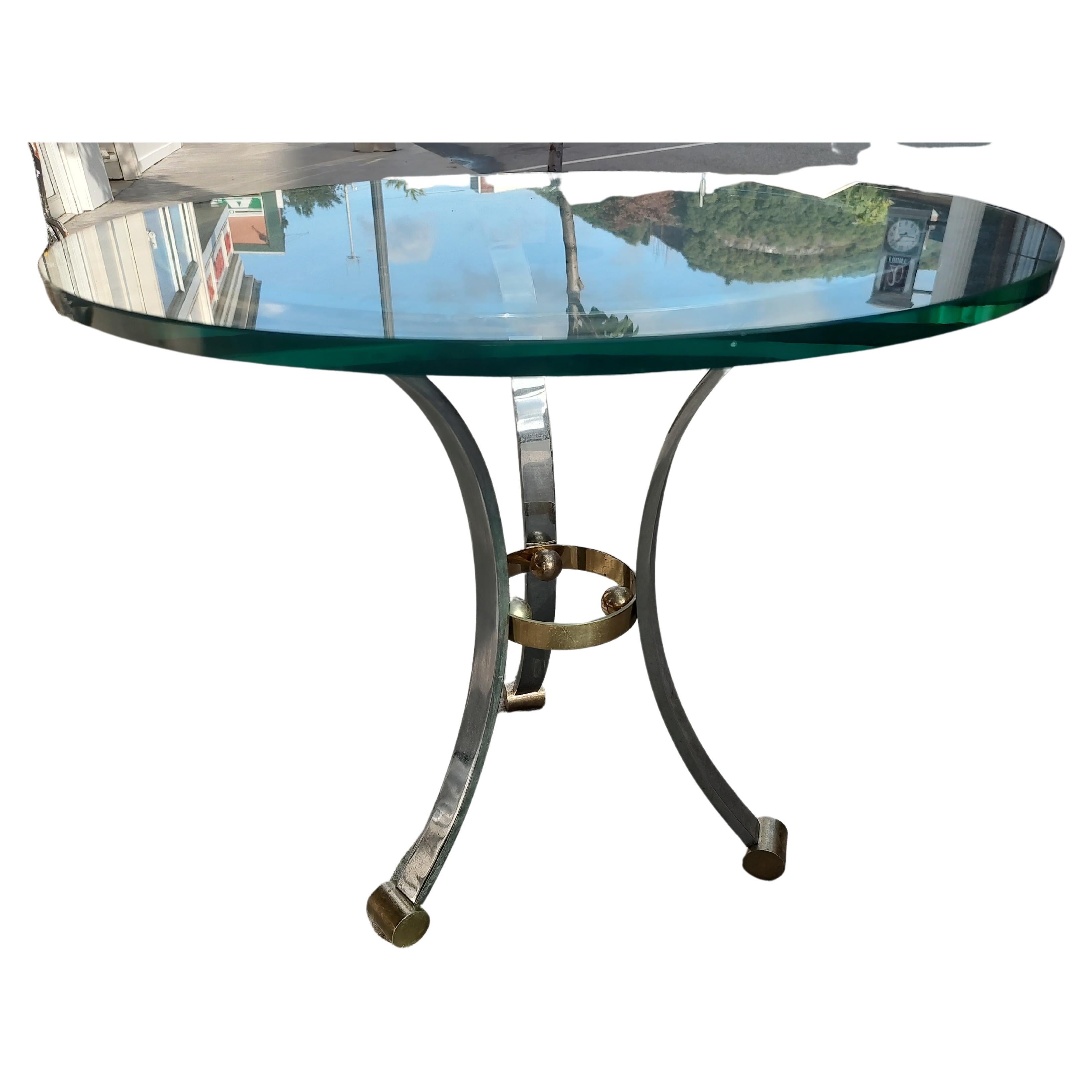 Fabulous side/end table attributed to Maison Jansen with 3 heavy chrome flat bar legs ending in brass cylindrical feet. Thick 5/8 glass top is near perfect, no chips. Quality piece. Will polish before leaving the gallery.