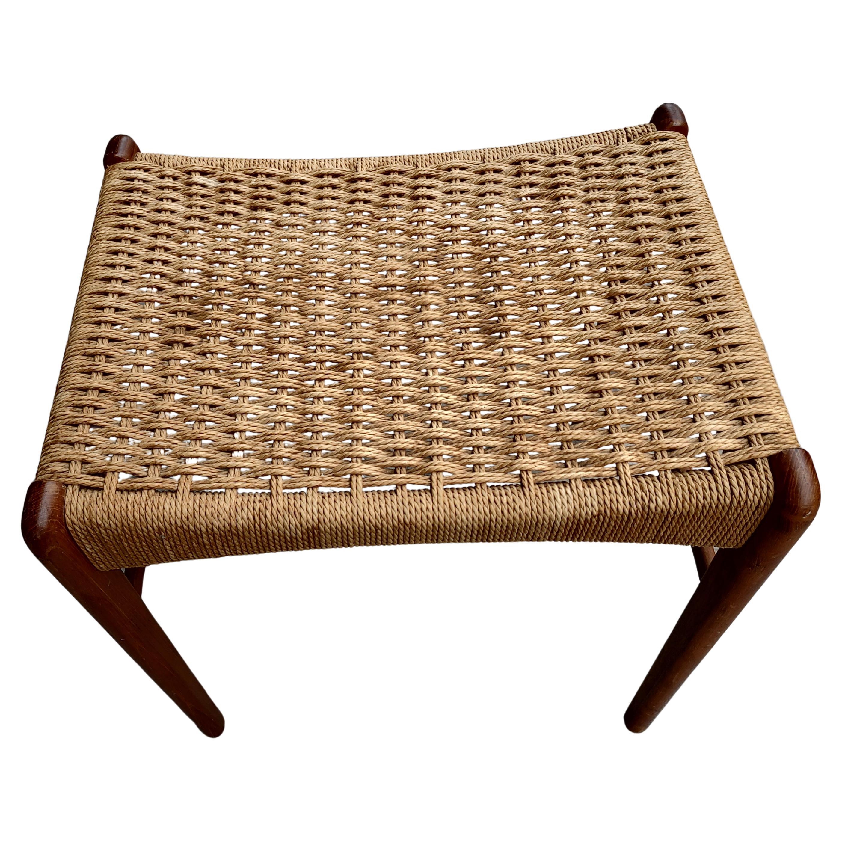Fabulous footstool from Denmark with a teak frame and a woven papercord seat. In very good condition with some water stains on the seat.