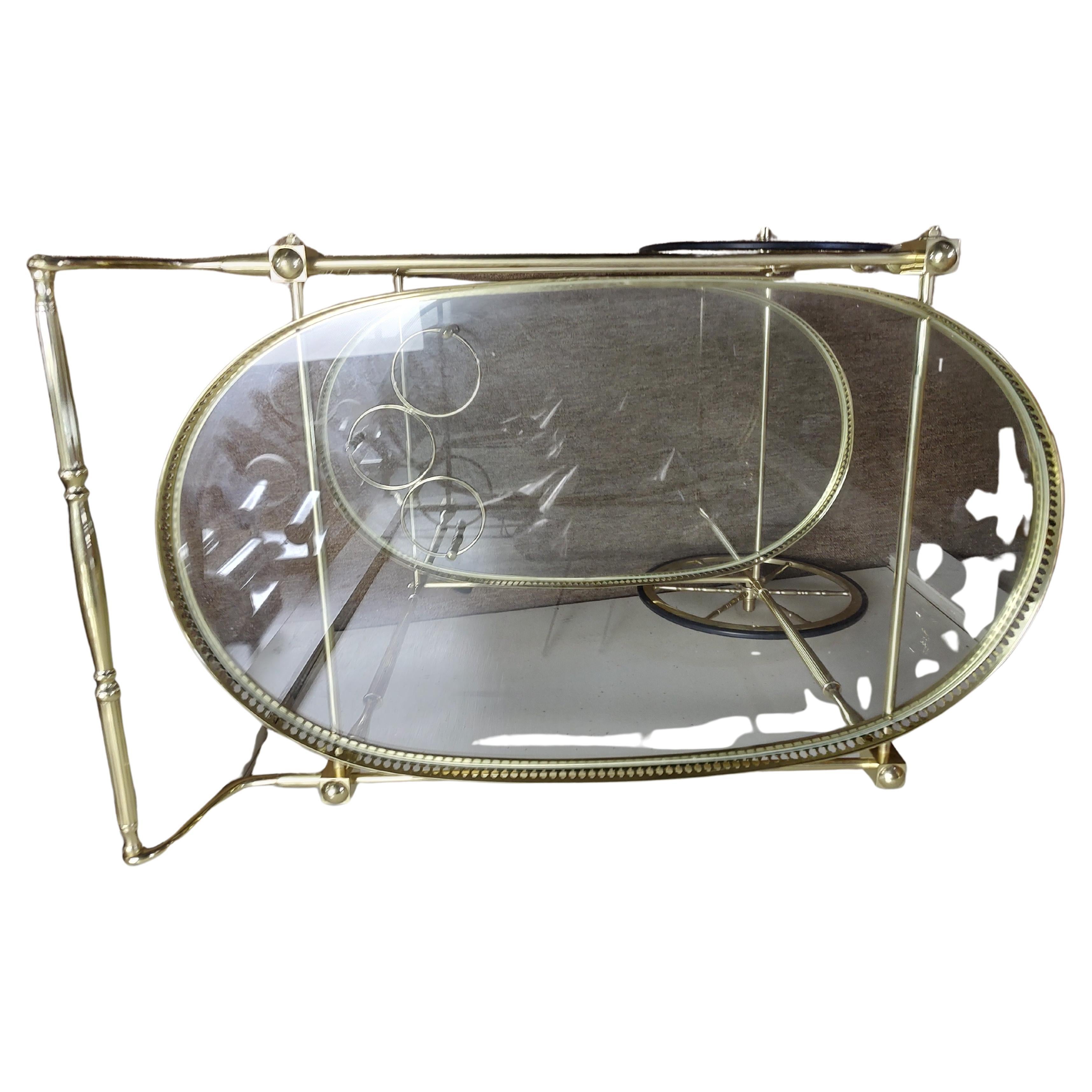 Fabuleux chariot de service de bar en laiton poli. Très bon style et en excellent état vintage avec une usure minimale. Bandes réticulées le long du périmètre avec des colonnes de jambes fantaisistes. Porte-bouteilles monté sur la tablette