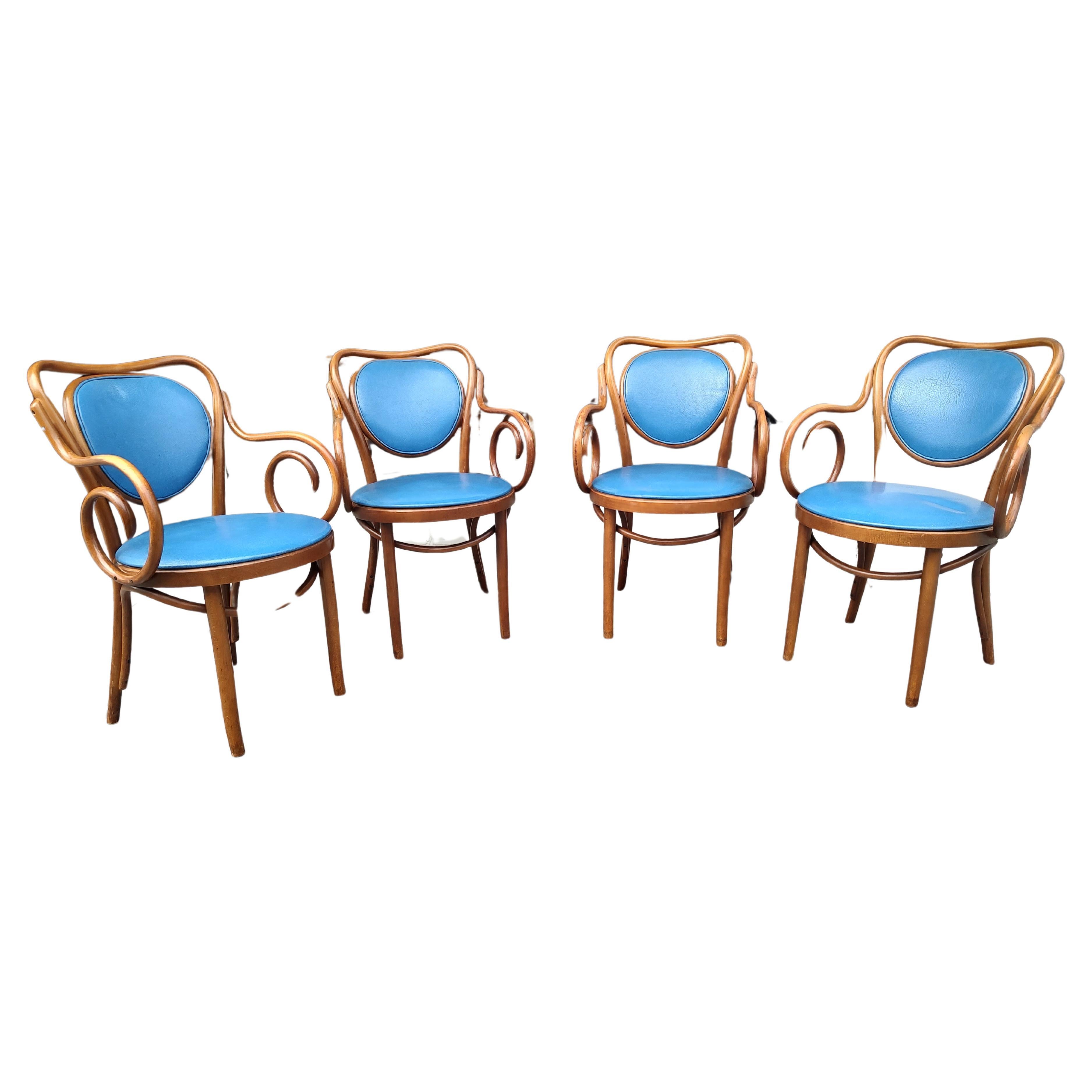 Fabuleux ensemble de 4 fauteuils de style Thonet en bois courbé. En excellent état vintage avec une usure minimale. Le vinyle bleu est une couleur vibrante et se change facilement. Les chaises sont également très confortables.