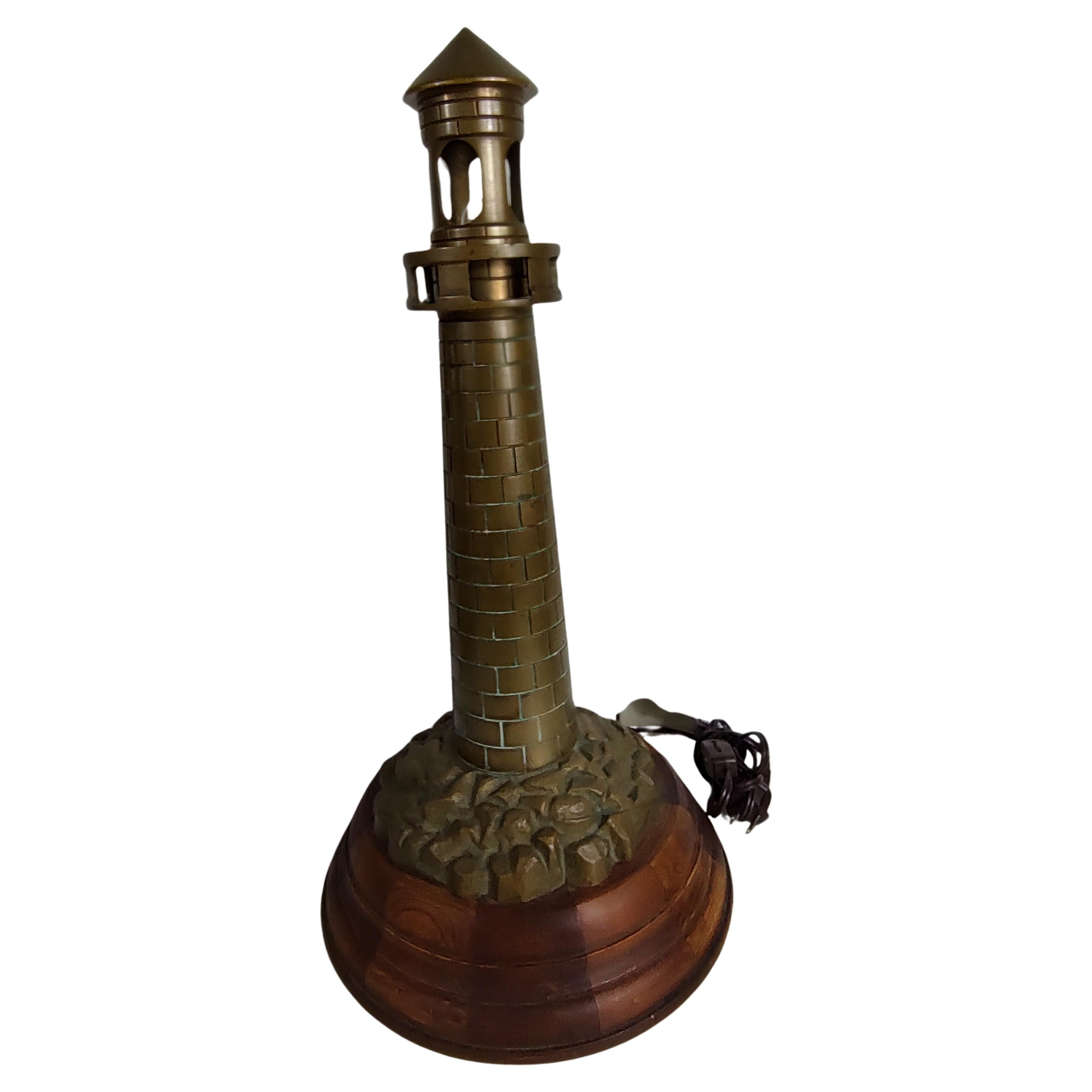 Fabulous cast bronze tall lighthouse in the form of a lamp. Cast rocks at the base which sits above a hand turned stepped wooden base. In excellent vintage condition with minimal wear.
