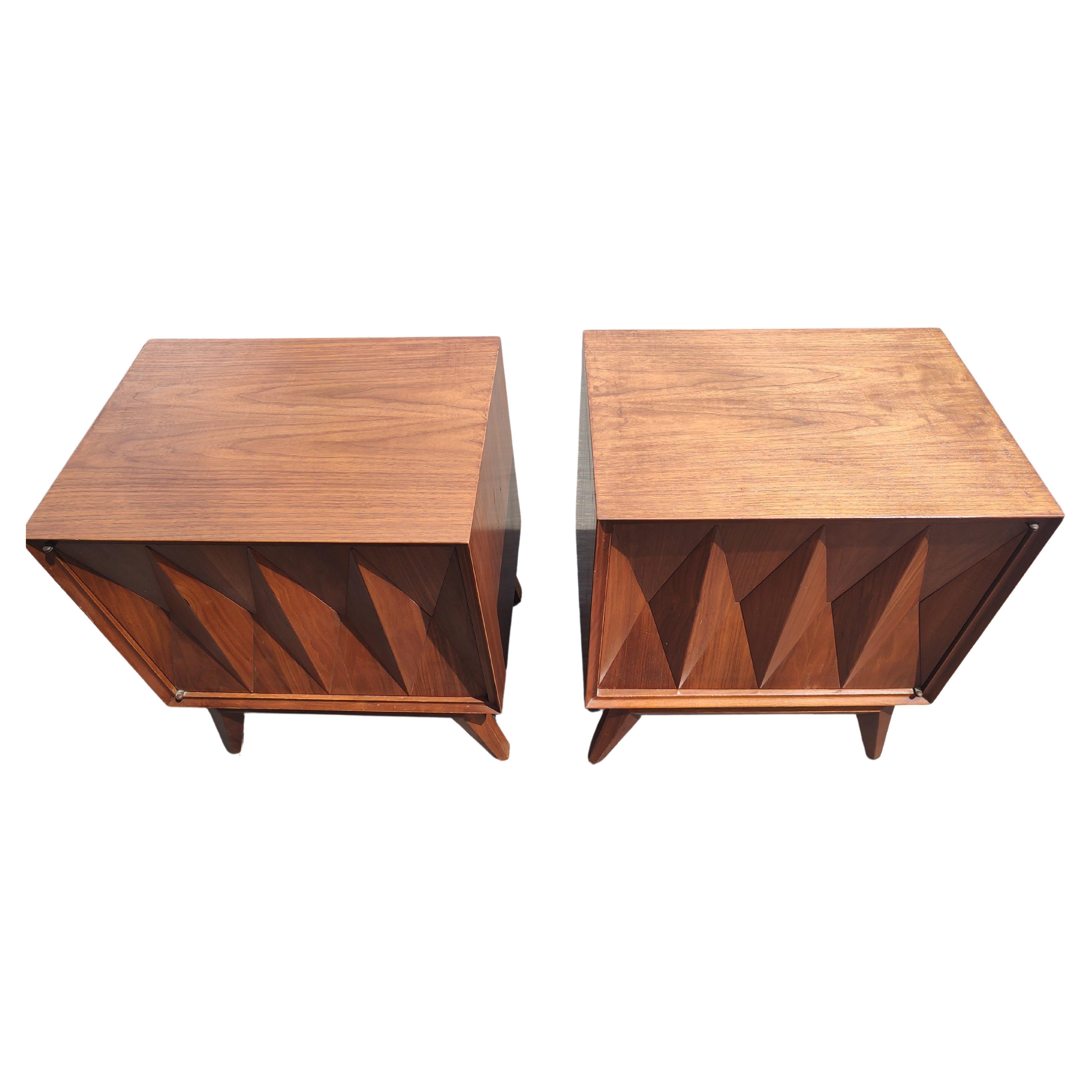 Fabulous pair of walnut diamond faceted single door night stands with an interior shelf. In excellent vintage condition with minimal wear. Such a beautiful design, push button doors open effortlessly from opposite sides. Priced and sold as a pair.