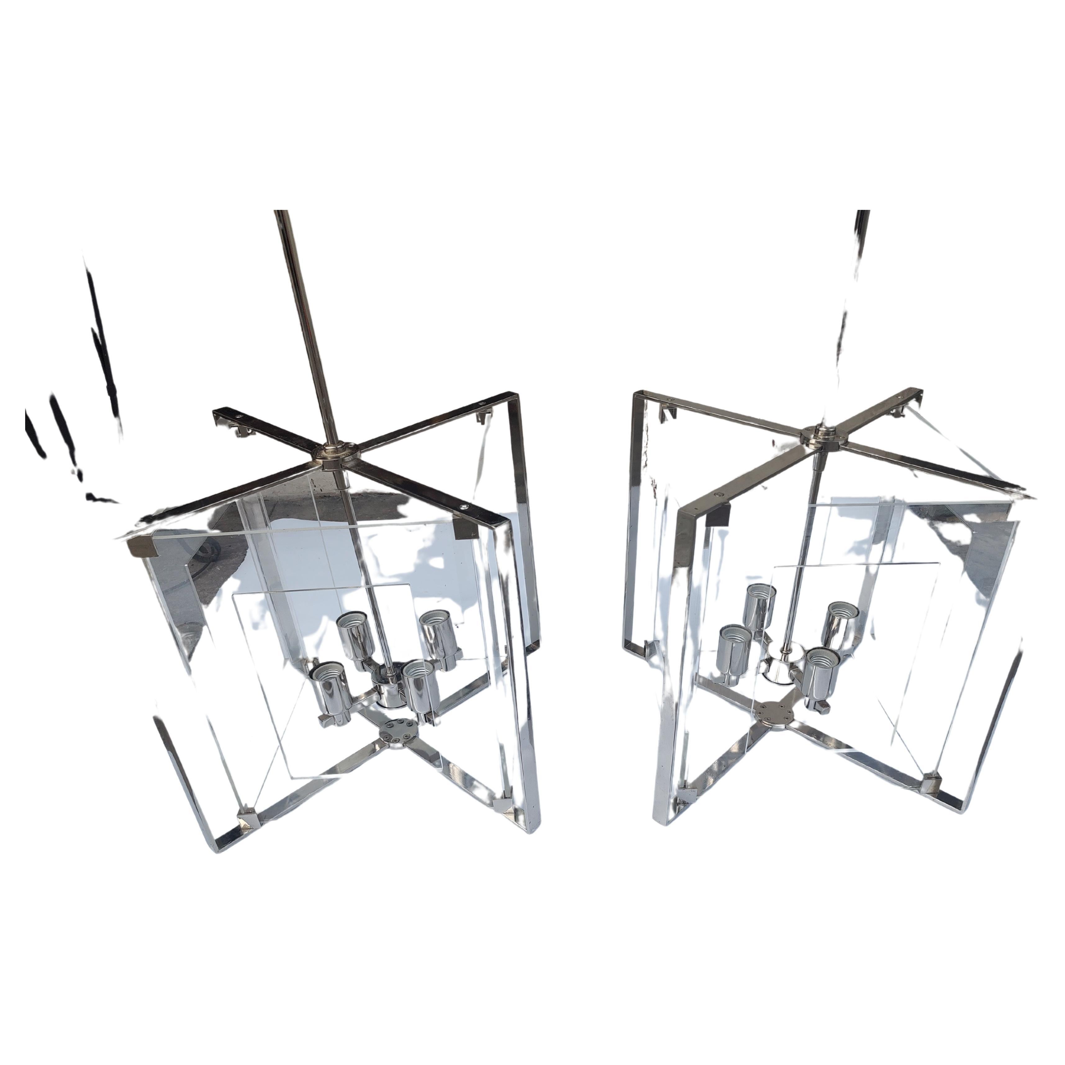 Fabulous modern and classical pair of pierced lucite with chrome frames hanging pendant lights. Beautiful style with 4 candlabra style bulbs to illuminate each fixture. Downrod and fixture combined is presently nearly 4ft but can be altered to suit
