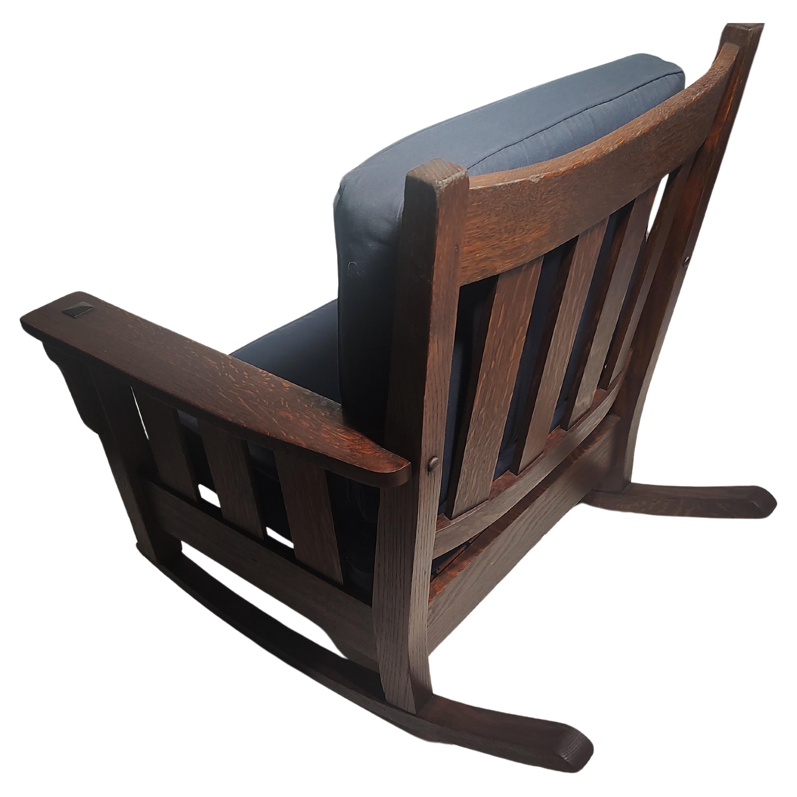 Fabulous heavy duty slatted rocking chair in excellent antique condition attributed to the Stickley Brothers furniture Co. Deep rich color to the quarter sawn oak. All pegged with mortise & tenon construction. Newer cushions with a navy blue cotton