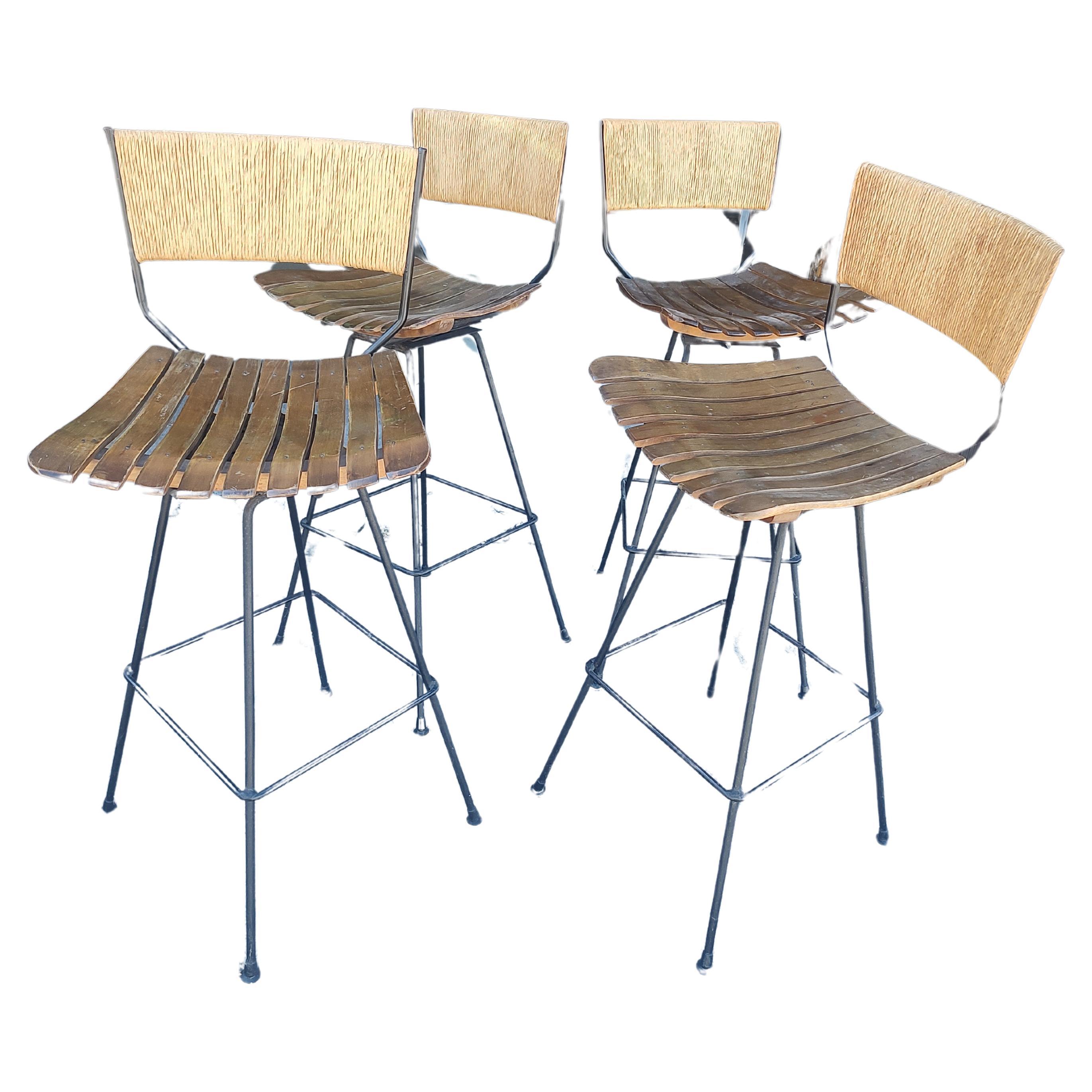Fabulous set of 4 iron framed bar stools with raffia wrapped backs and maple slatted seats. They swivel also!  In excellent vintage condition with minimal wear, plastic glides on all feet except one which we have replaced with a similar example.