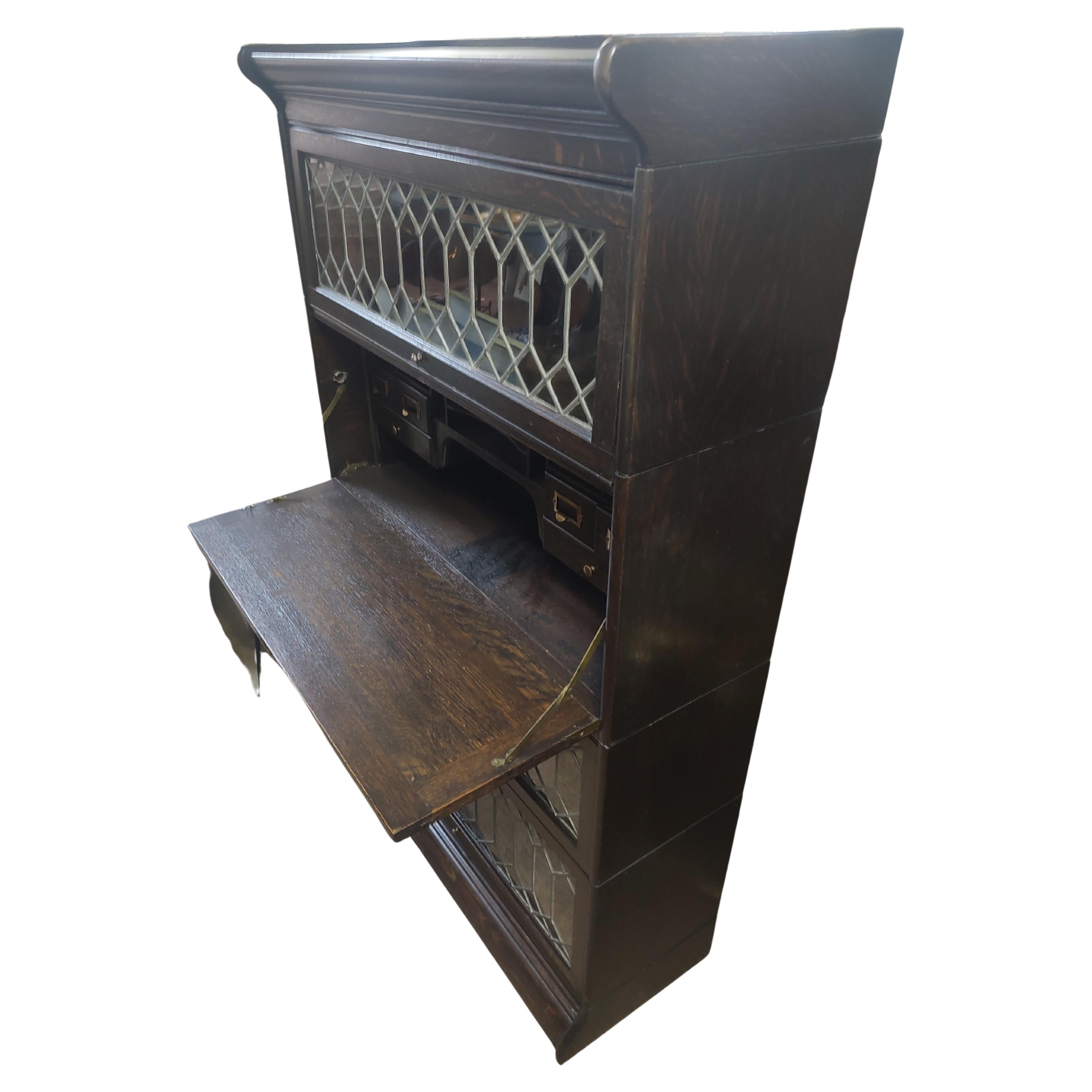 Fabulous simple and elegant 3 section leaded glass bookcase with a drop down desk and compartment drawers. Total of 6 sections all in oak which includes a top & bottom 3 leaded glass sections and the desk. Desk lid, writing surface drops down to a