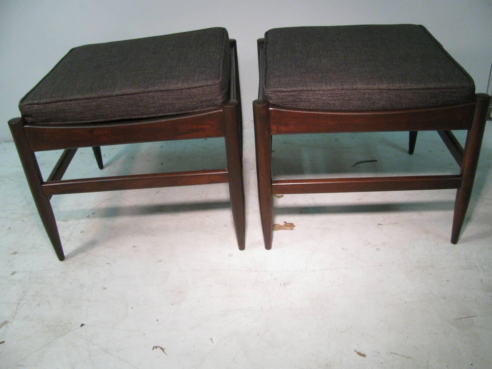 Simple and elegant Pair of ottomans with removable cushions which are newly refinished and reupholstered. Sculpted wood with turned legs.
