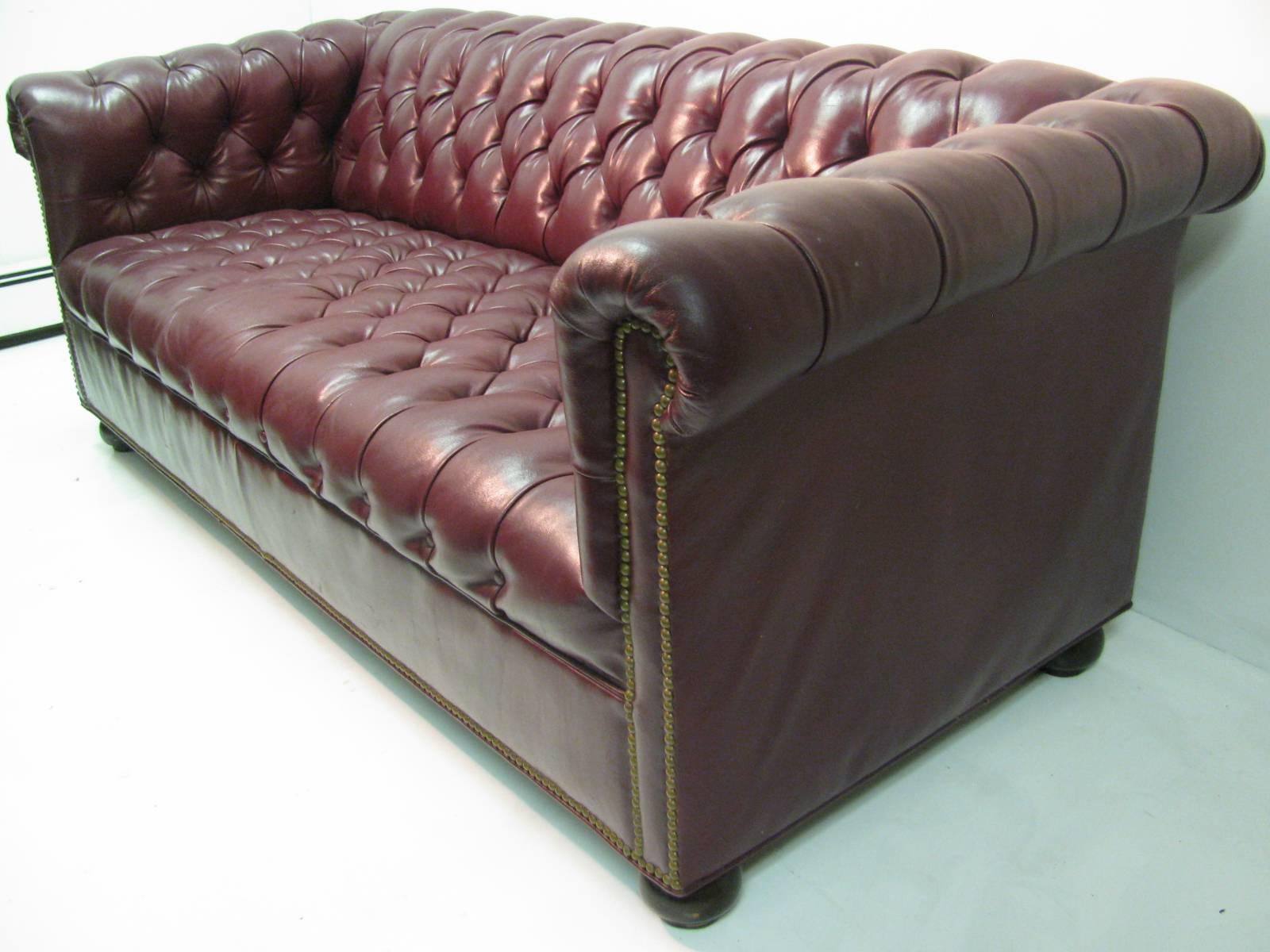 Classic mid century Chesterfield sofa in red burgundy leather. Hardwood bun feet.
