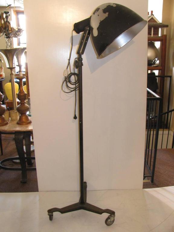 Tall Scoop Industrial lamp with three caster wheels for great mobility. From a movie set, television or a theatre production. Rewired. Adjustable shade will tilt and lock. Height adjusts up to ten feet tall. Disassembly for shipping.