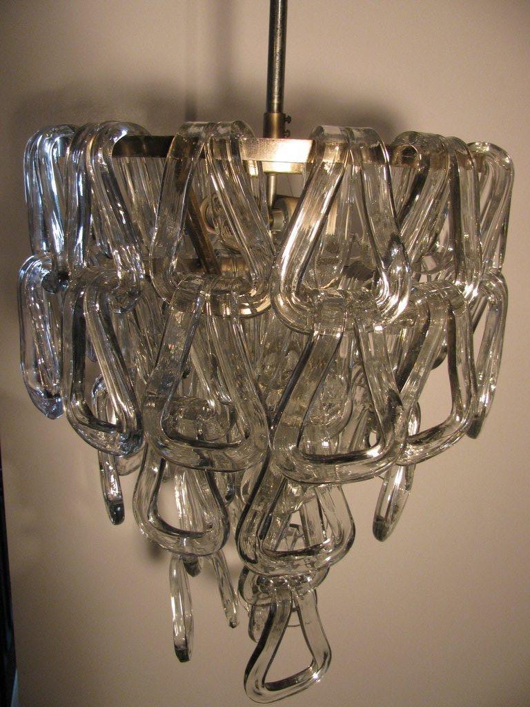 Elegant crystal glass chandelier from Mazzega. 51 glass crystals in the form of bent rings which drape over three concentric rings. We have arranged crystals in two variations, one square, one tapered. These are heavy and thick, but give the