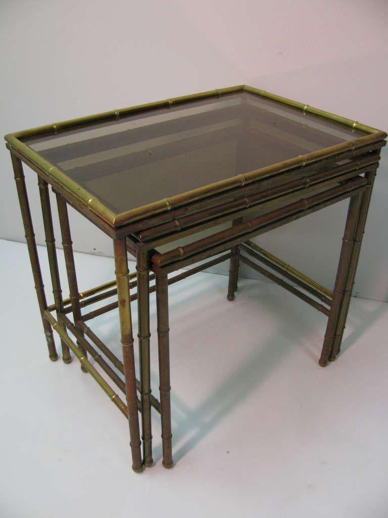 Set of three solid brass nesting tables with original glass tops. Created in the faux bamboo style, tables are stamped made in Italy. Brass has tarnished. Brass polishing available.