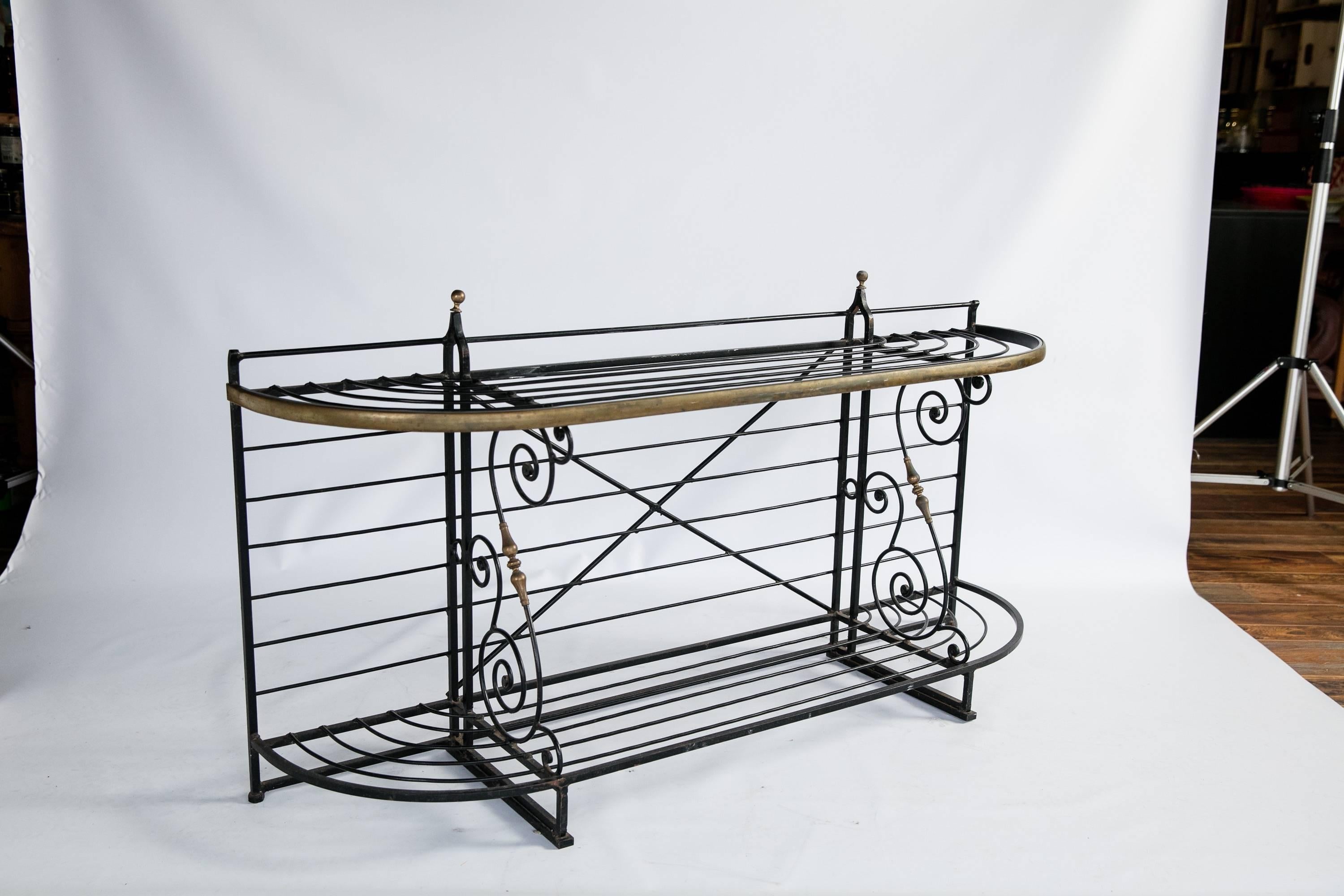 French wrought iron baker's rack with brass detailing. The rack has two shelves; the lower is divided into three compartments. Top shelf, 59.5