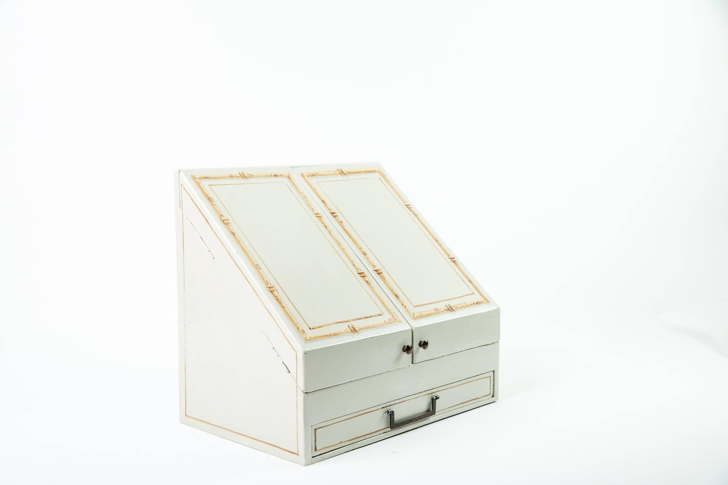 A grey-painted wood writing stationery caddy with ten compartments designed to contain a variety of writing utensils and notepaper. The interior of the box is concealed by two doors, each painted with trompe-l'oeil bamboo detail. Oil-rubbed bronze