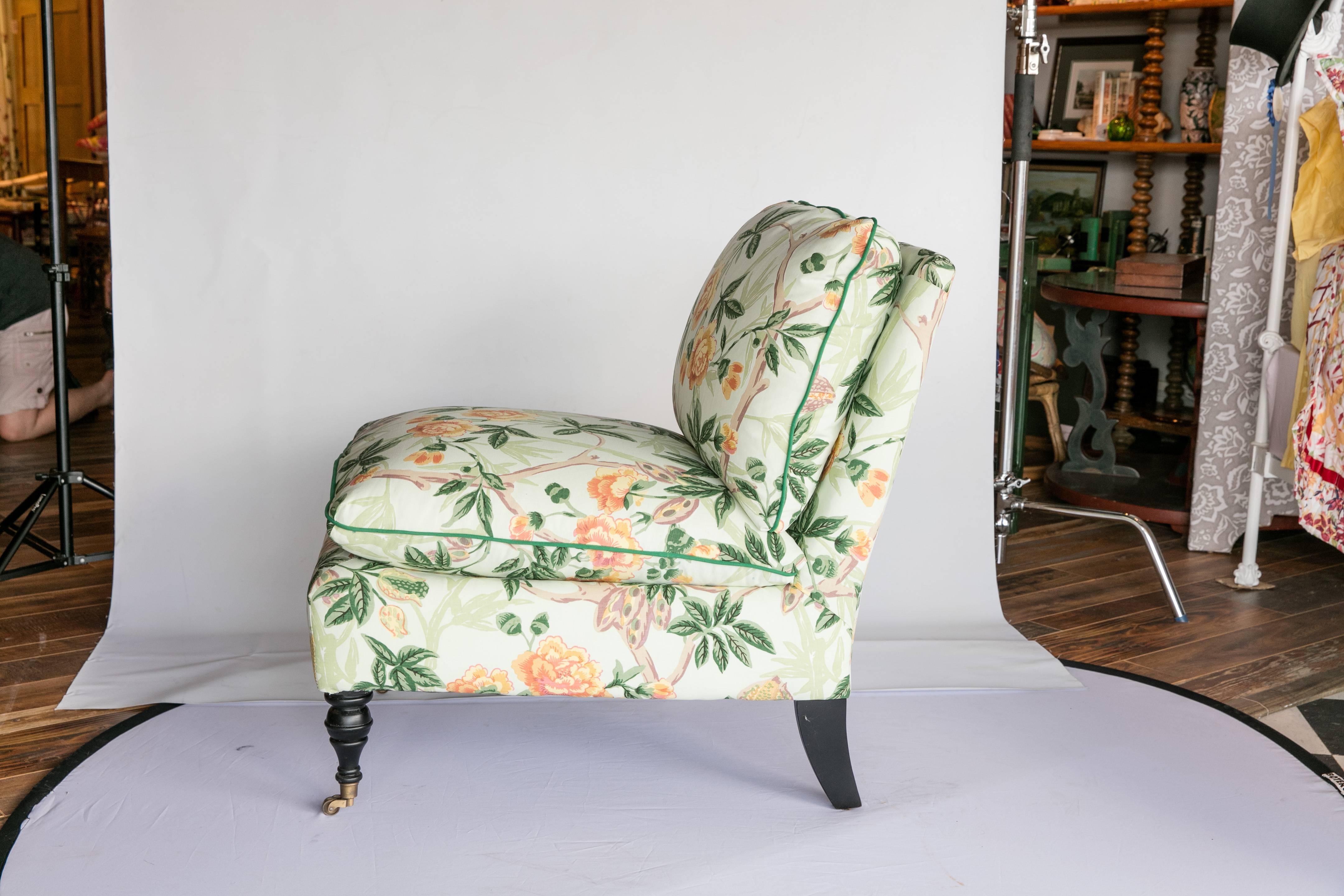 A custom 20th century Edwardian-style slipper chair newly upholstered in a cotton Brunschwig and Fils chinoiserie-style floral print with a light green/blue ground. The front legs are turned and have brass casters. Seat and back cushions are