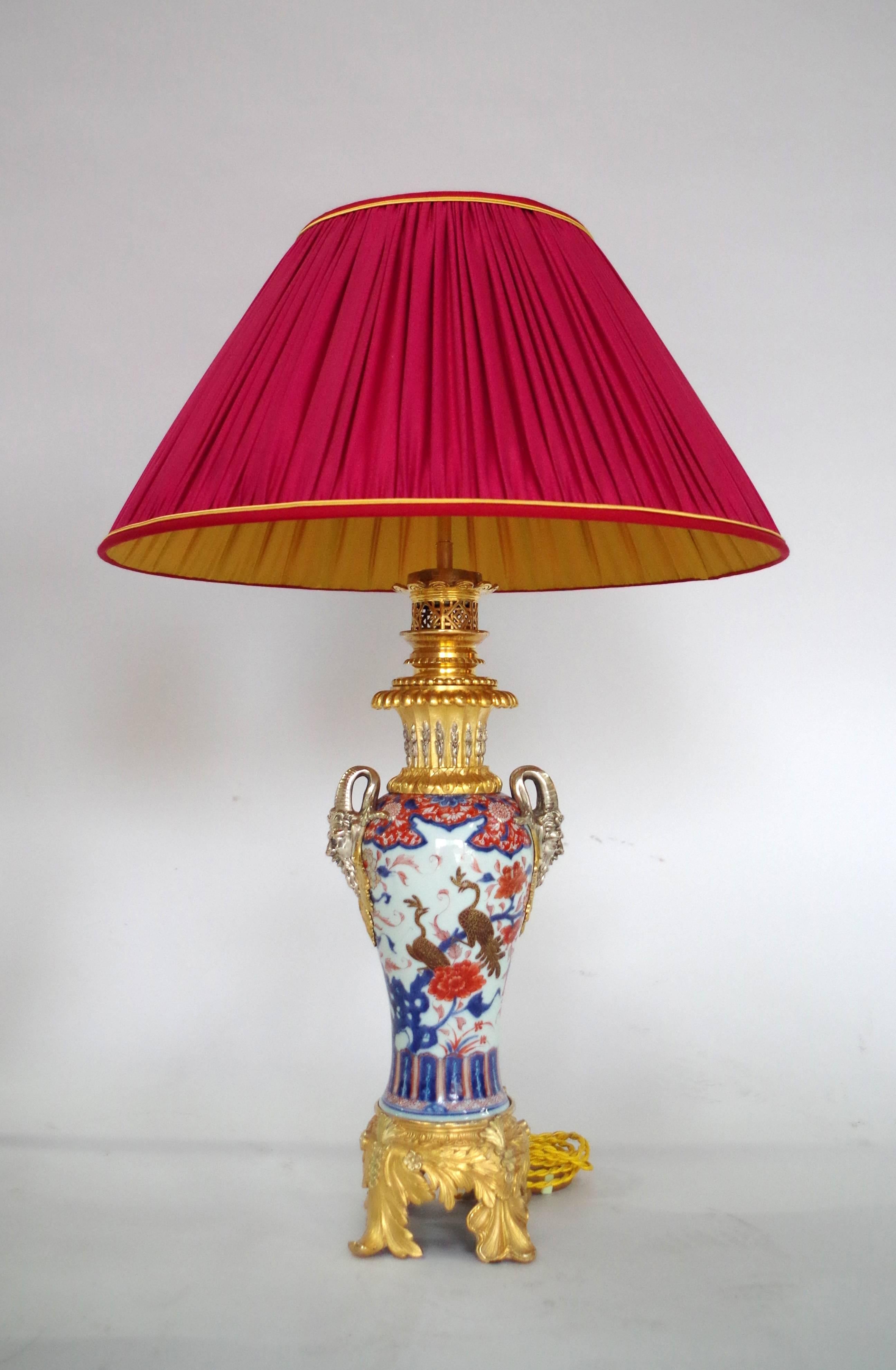 

Pair of large baluster-shape porcelain lamps. Imari decoration with gold highlights representing peacocks on branches on a plum tree and chrysenthemum background.
Finely chiseled, gilt and silvered bronze mount with an acanthus leaves base and