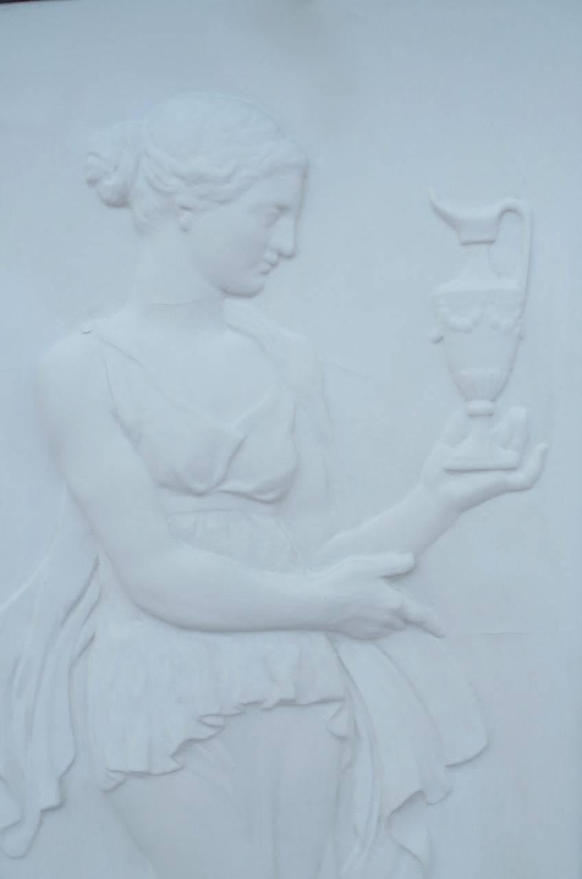 Pair of bas-reliefs in white plaster figuring two antiques vestals. Both in profile, one holding in her hand a small jar and the other one holding a cup which releases, probably, burning incense. They are both hair dressed and dressed like in