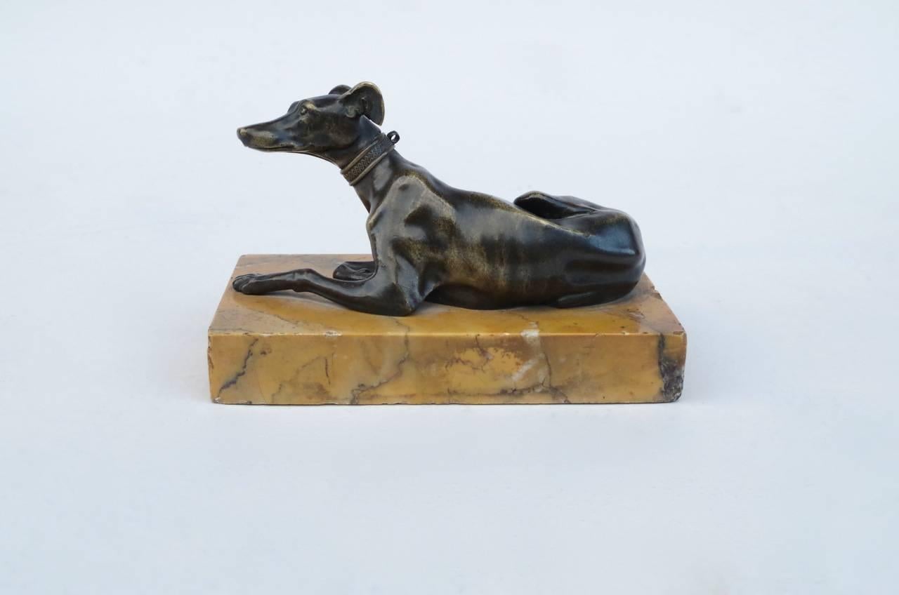 Thomas Weeks' model reclining whippet sculpture in bronze on a yellow Sienna marble base.
Work from the late 19th century.

For a similar of recumbant greyhounds see the sale of the Collection of Robert Hatfield Ellsworth; Christie's, New York,