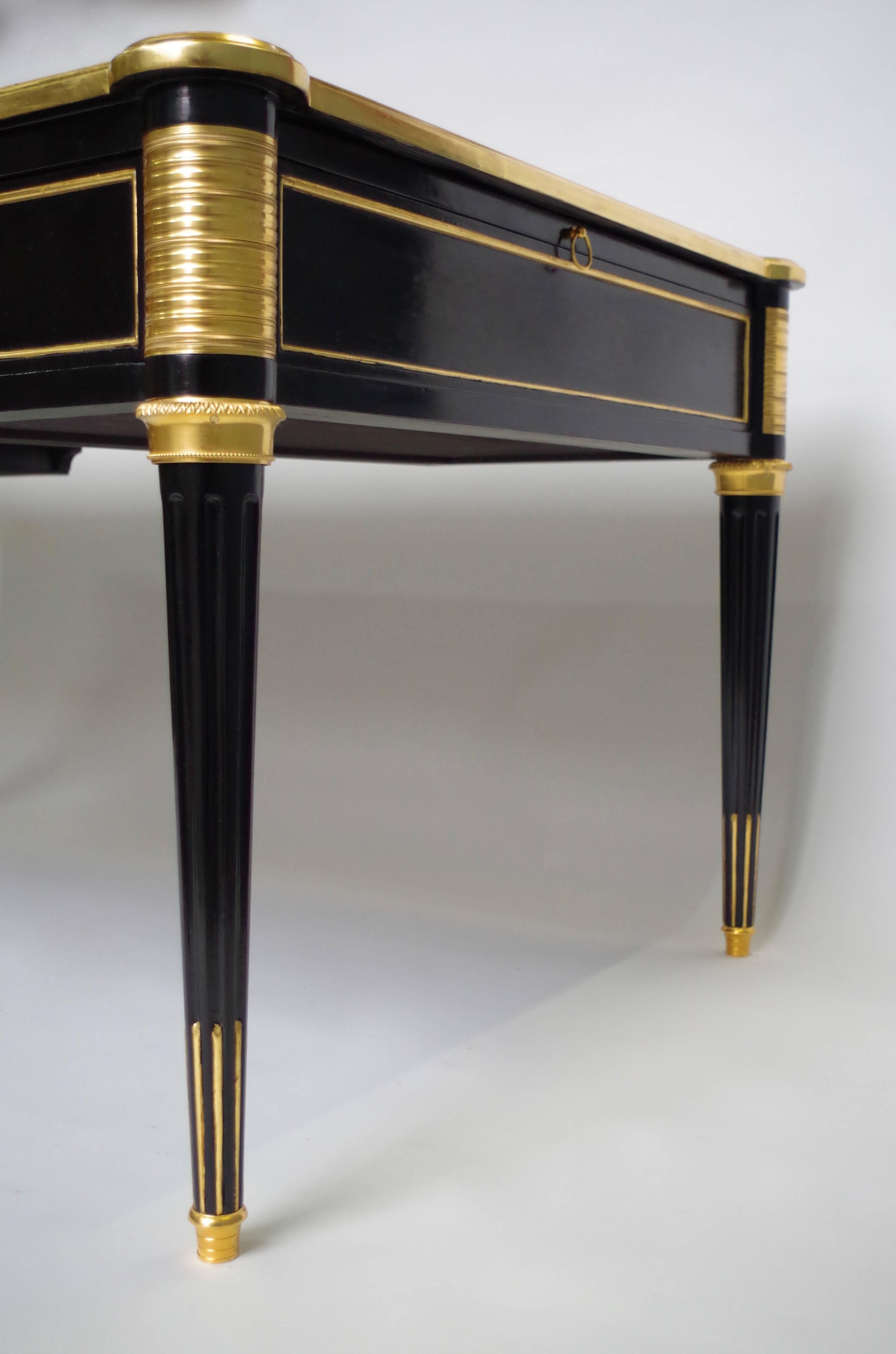 Large Louis XVI style flat desk in black lacquered mahogany gilt with golden leaf. Model with two writing-slides and standing on four fluted legs ending with a gilded shoe.
Three drawers on his apron, adornated with gilded bronzes on angles and