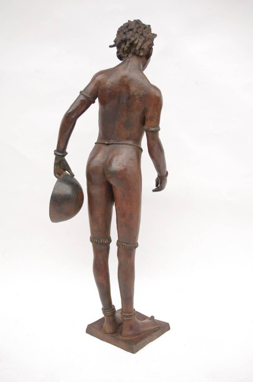 Patinated feminine bronze sculpture titled “Young Lady with a Gourd” (“La jeune fille à la calebasse”) representing a black woman holding a gourd, only wearing a loincloth and jewels at the ankles, knees, neck, forearms and wrists.

Signed “Darbaud”
