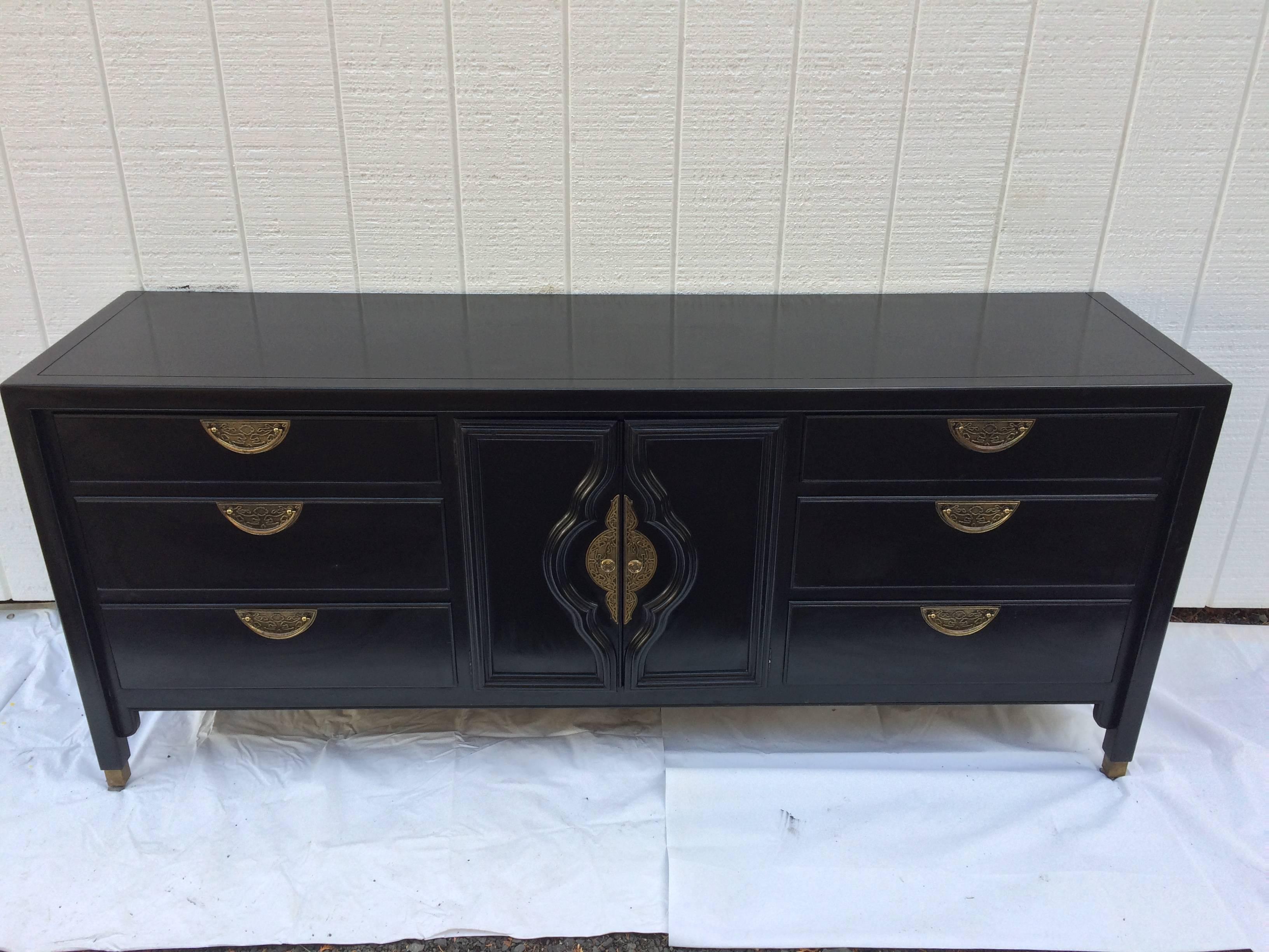 Hollywood Regency dresser in the style of James Mont for Century. Lots of storage to this solid wood black beauty. Gorgeous brass pulls make up this Classic piece. Matching mirror also available as well as nightstands.