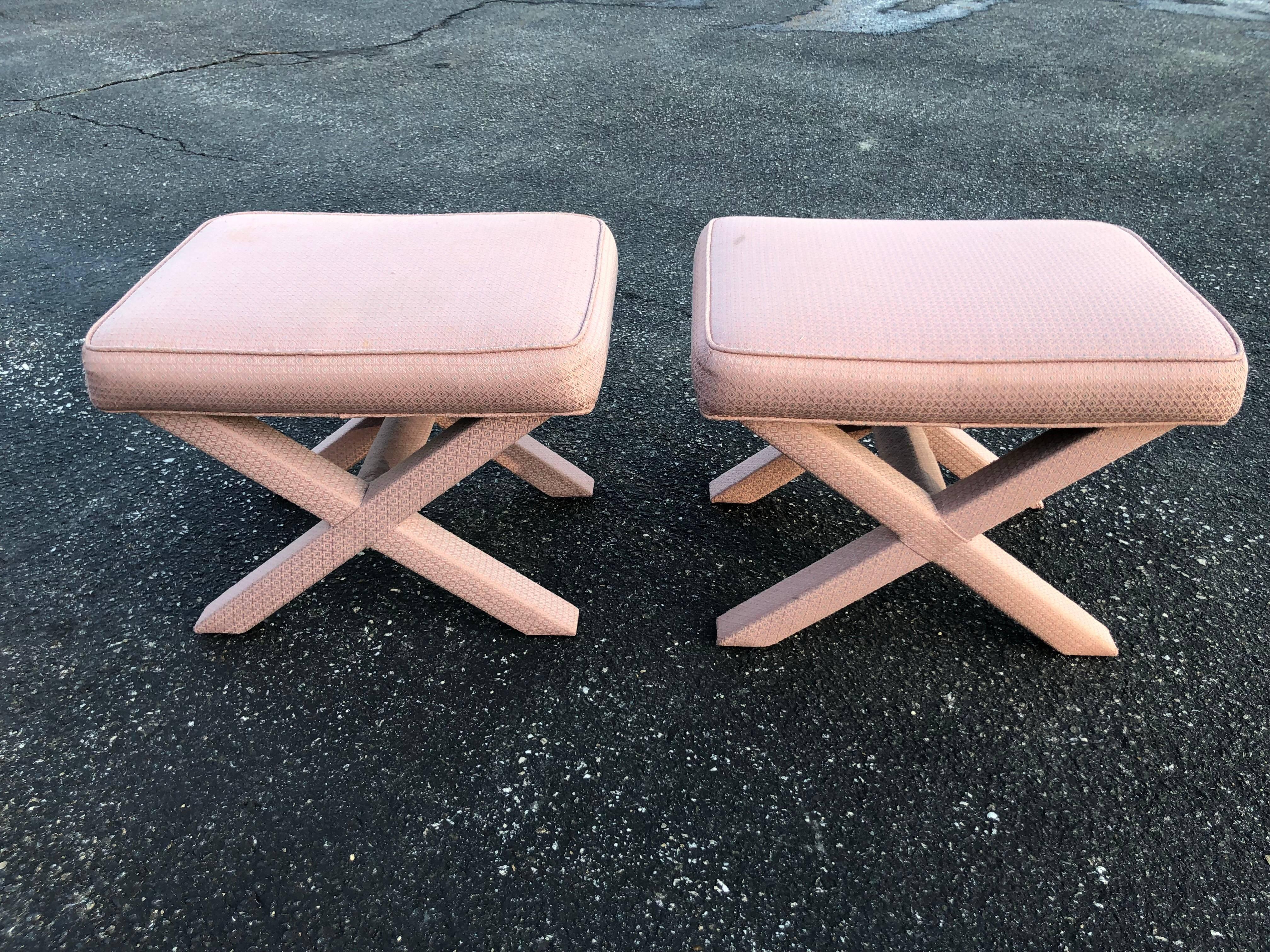 Pair of X-base stools or ottomans in the style of Billy Baldwin. Pale pinkish mauve upholstery. Could use a recover. Some marks on stools. See photos. Hollywood Regency design but of the midcentury period.
   