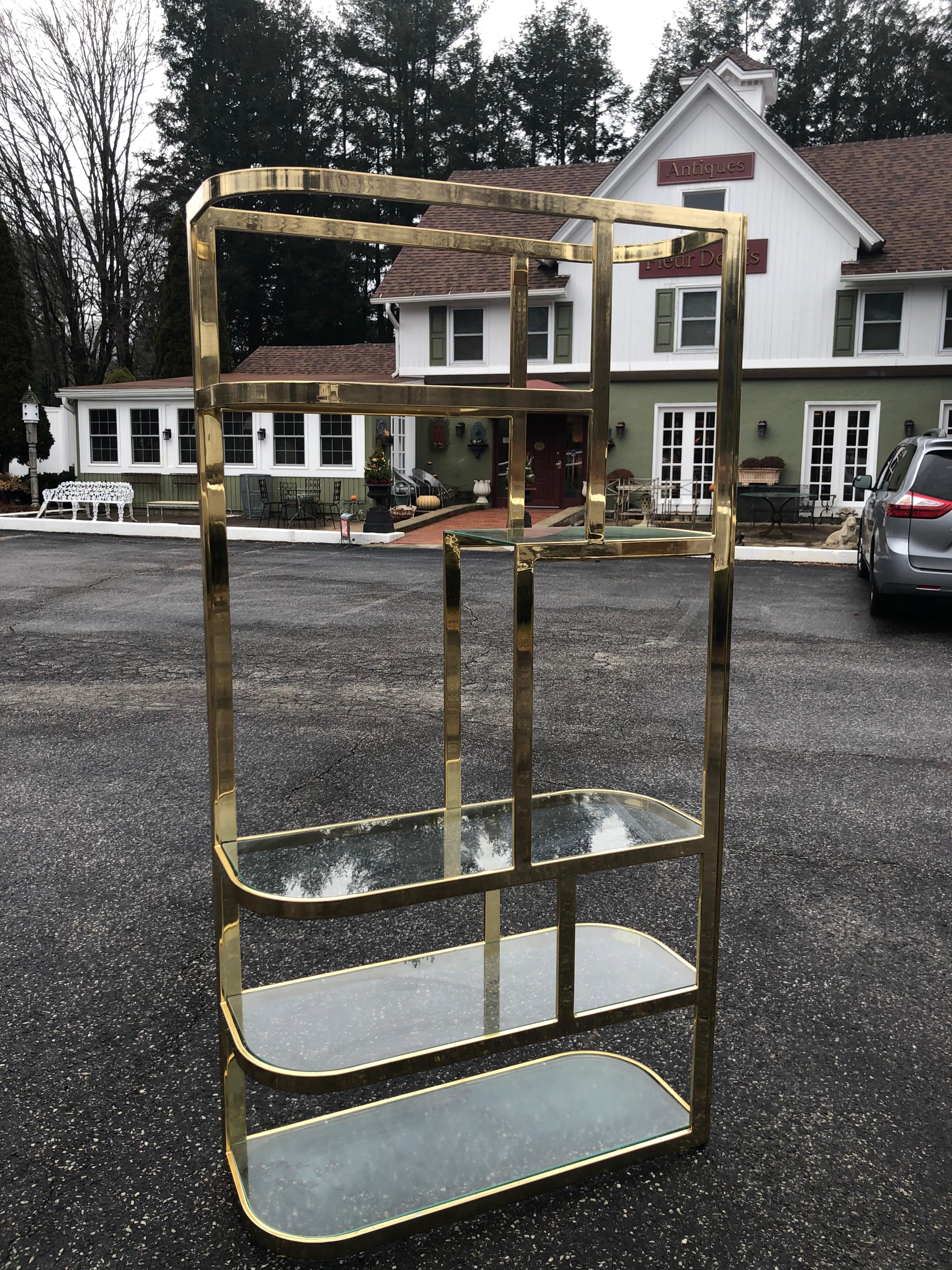 Pair of Hollywood Regency brass and glass Étagères. This listing is for a matching pair of two. We only have a photo of one but there are two. Extraordinary shape and pizzazz. Great designer item to jazz up any living room or study. Thick banded