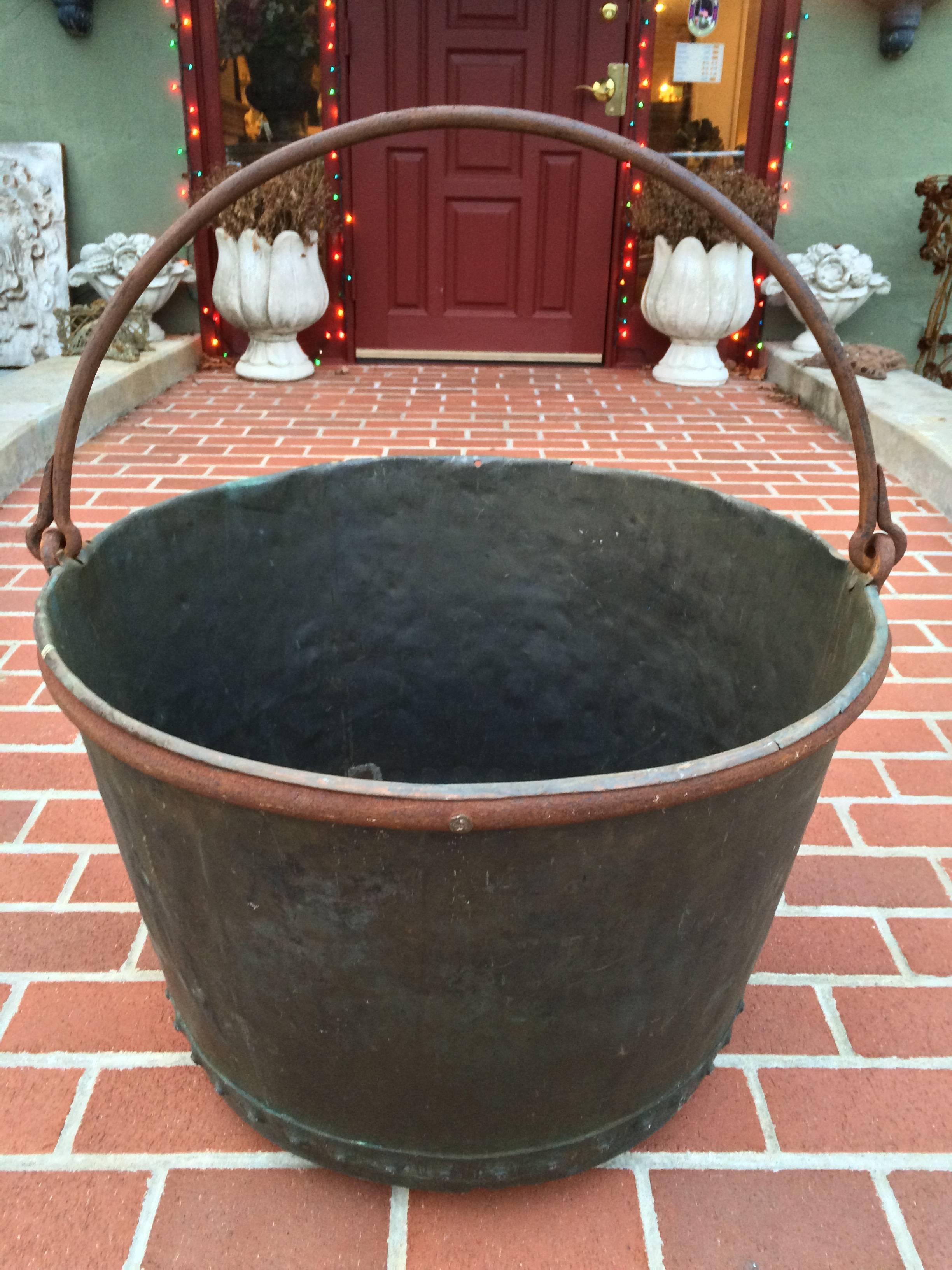 A large early 19th century riveted copper apple butter cauldron with forged iron handle. Lovely aged blue-green patina. One old repair as shown. Base is 19