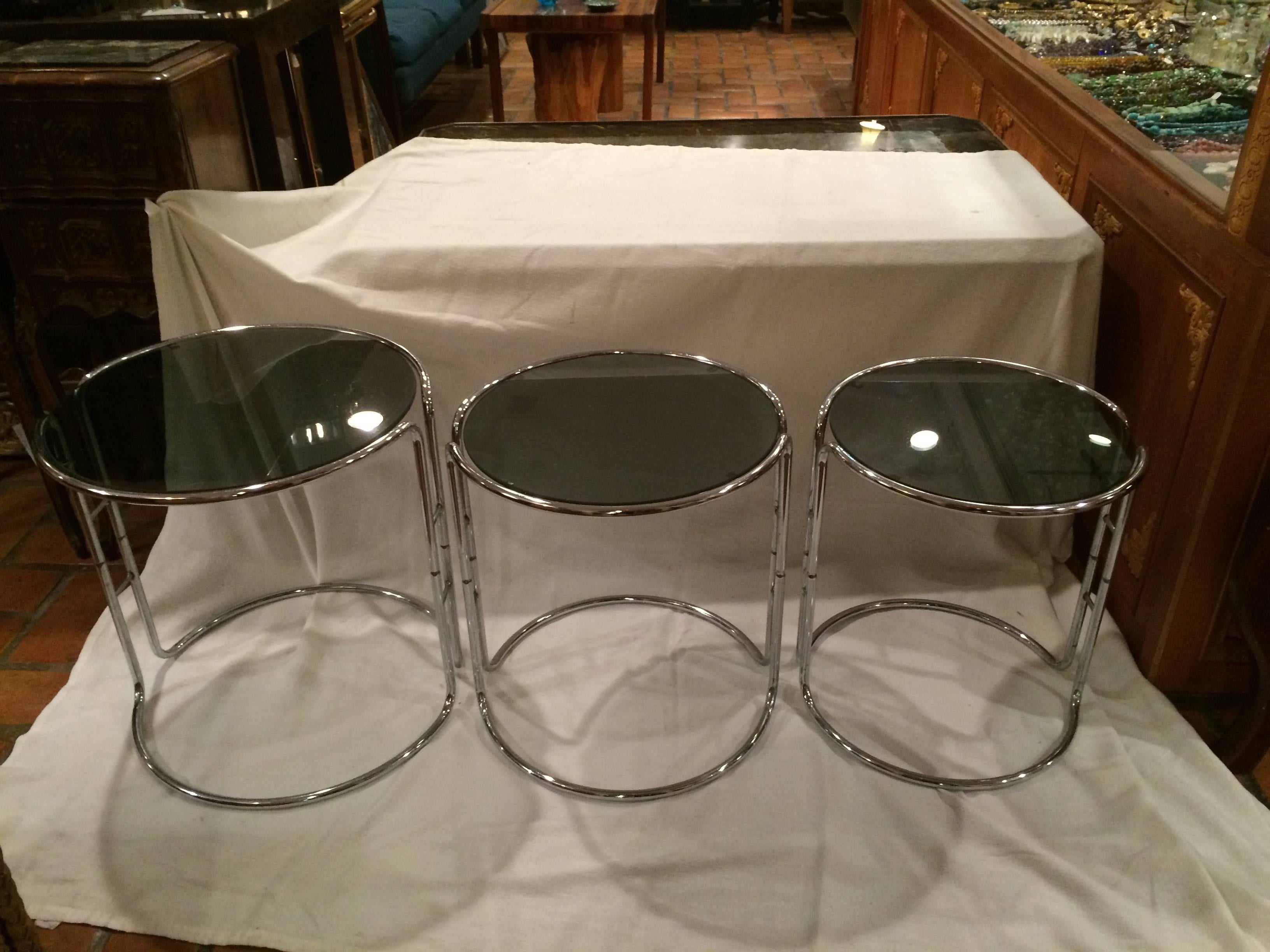 Set of three Milo Baughman chrome and smoked glass stacking tables. Fabulous lines make up this head turning trio. One table fits over the other so they are stack-able, more than a nesting set. Great for small, limited spaces.