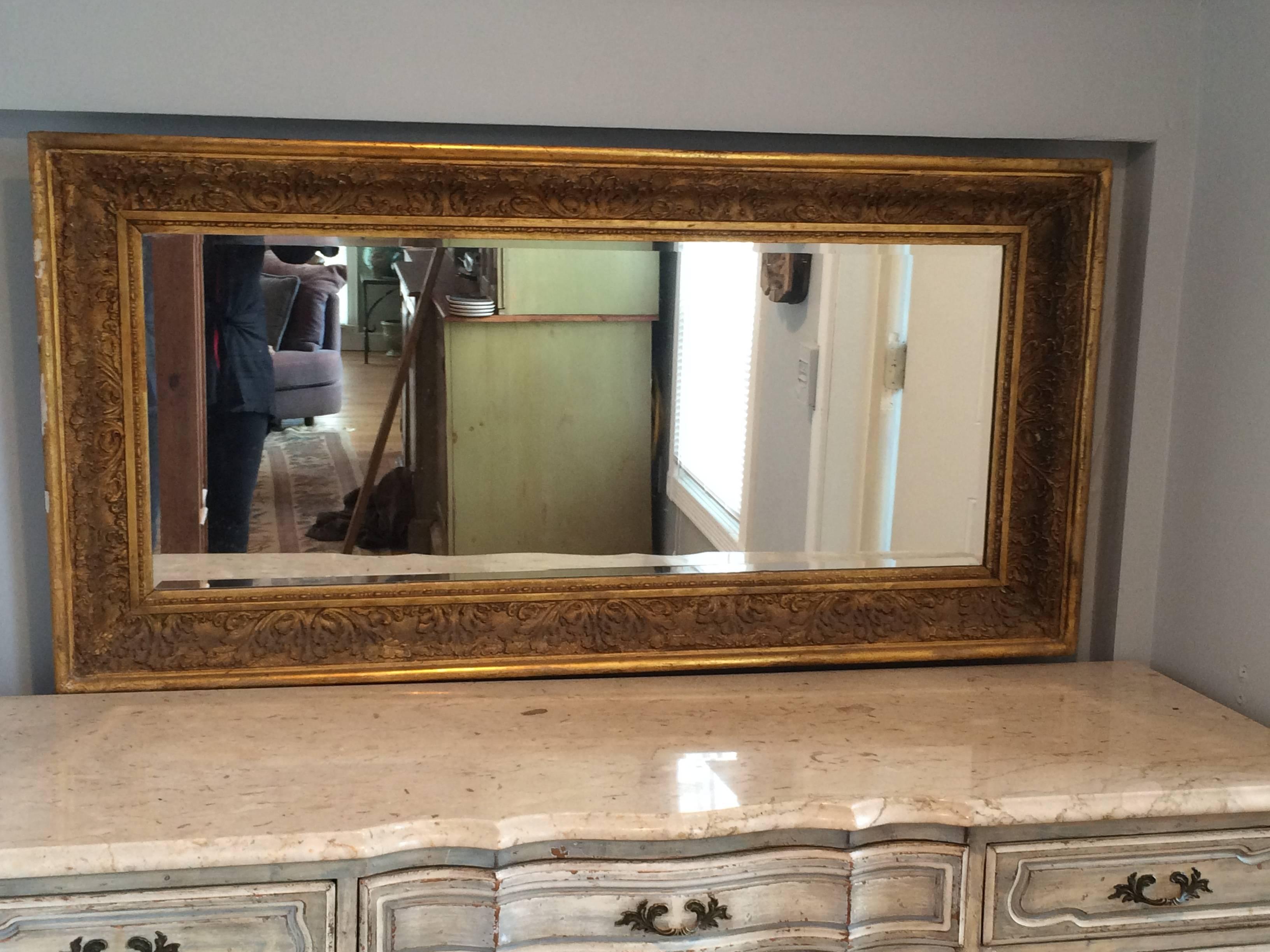 Large antique gilt mirror with half in bevel. Perfect for above a Mantel or foyer entrance. Can be hung vertically or horizontally. Thick, gilt and carved gesso design.