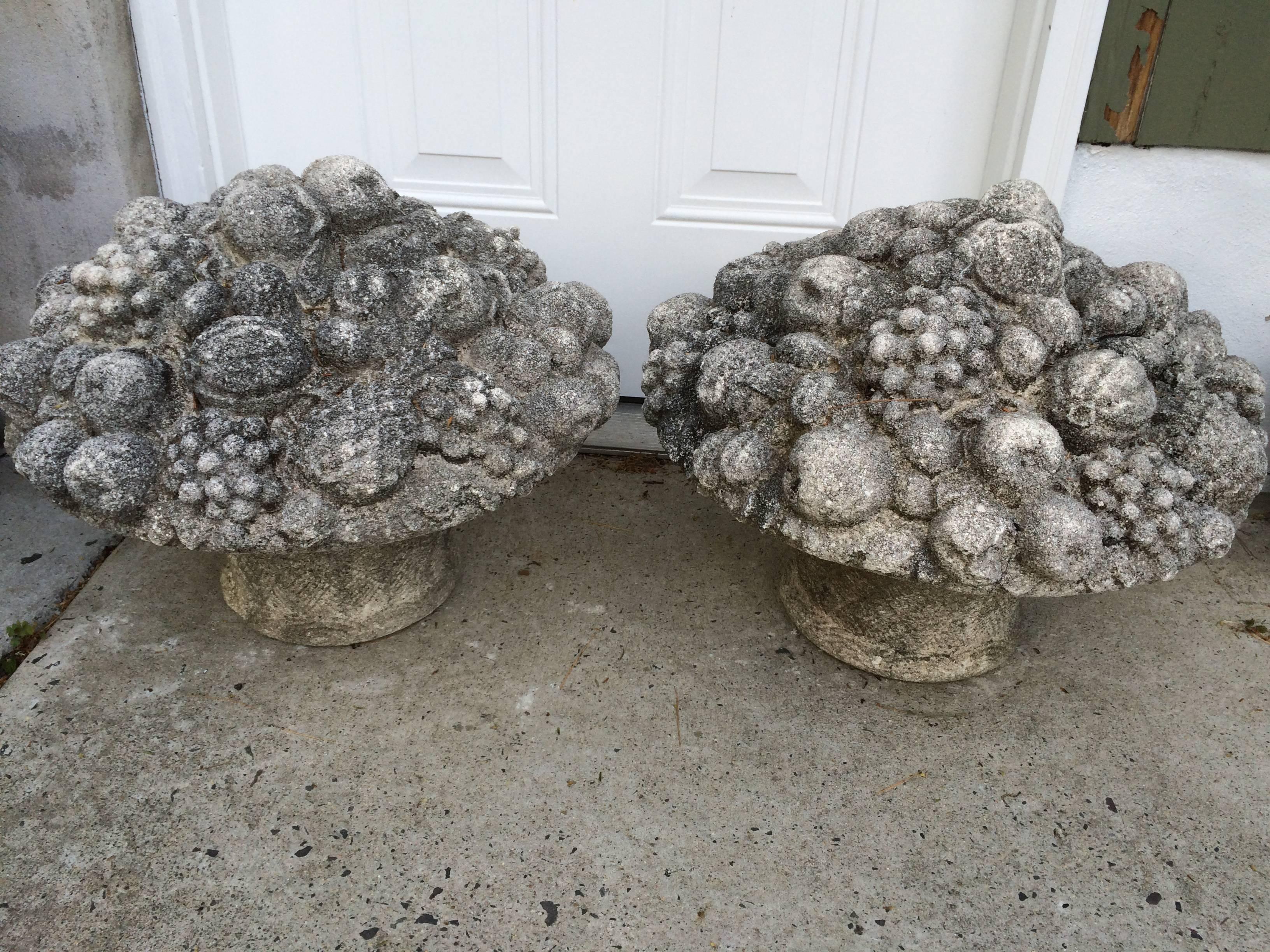 Monumental pair of antique cast stone fruit and flower baskets. Lovely aged patina to these beautiful detailed bouquets. These incredible garden ornaments would complement any estate. Each basket measures: 16.50
