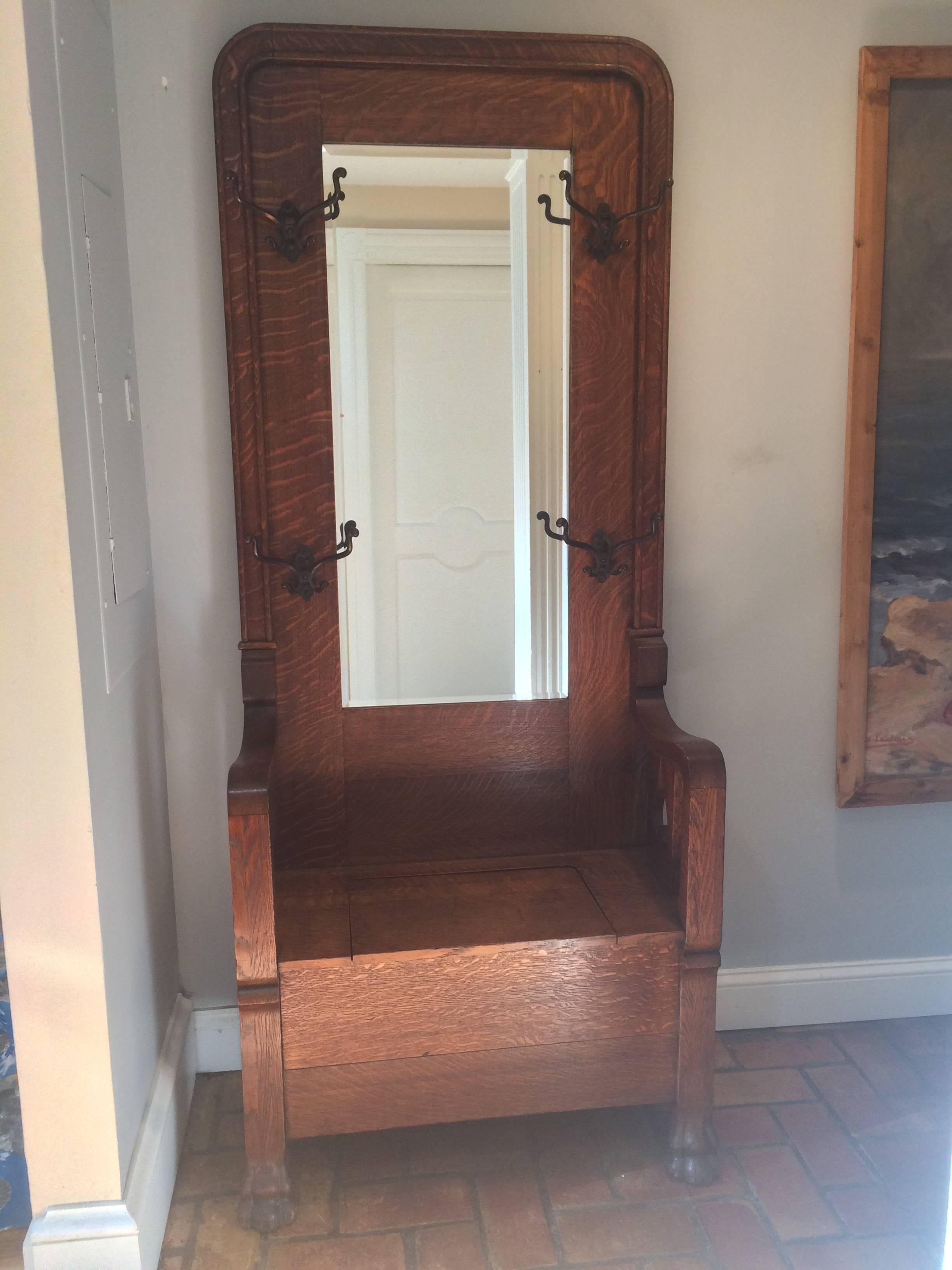 Antique tiger oak hall tree with storage. This beautiful quarter sawn piece will complement any entryway or mudroom while being completely functional. With four original vintage hooks to hold coats, purses, scarves and umbrellas and a one inch