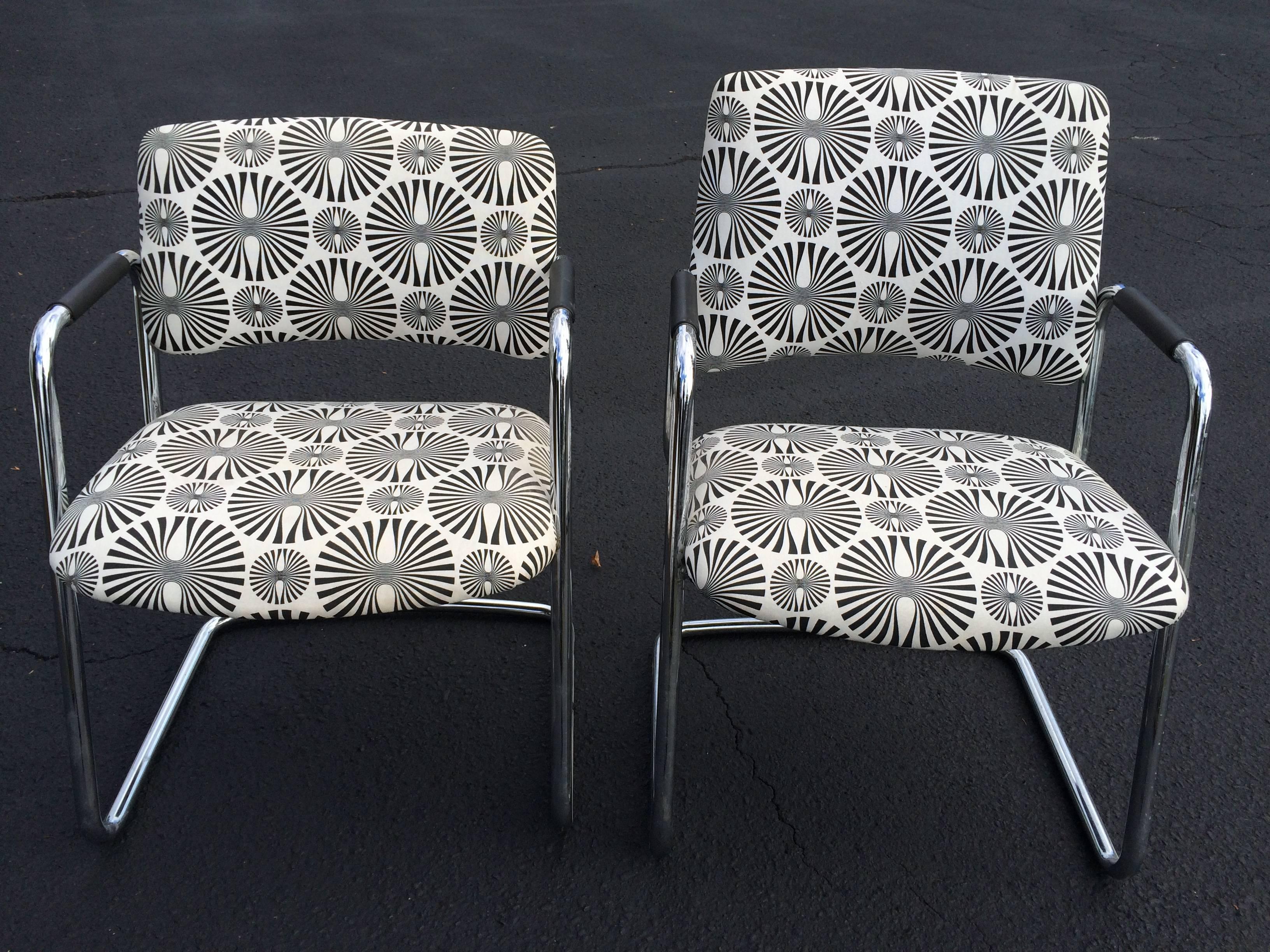 Pair of Mid-Century style optical art chairs in black and white. The chairs are covered in a cotton fabric with a psychedelic print. One chair has a high back and one a lower. These were used in an office with the high back chair behind the desk and