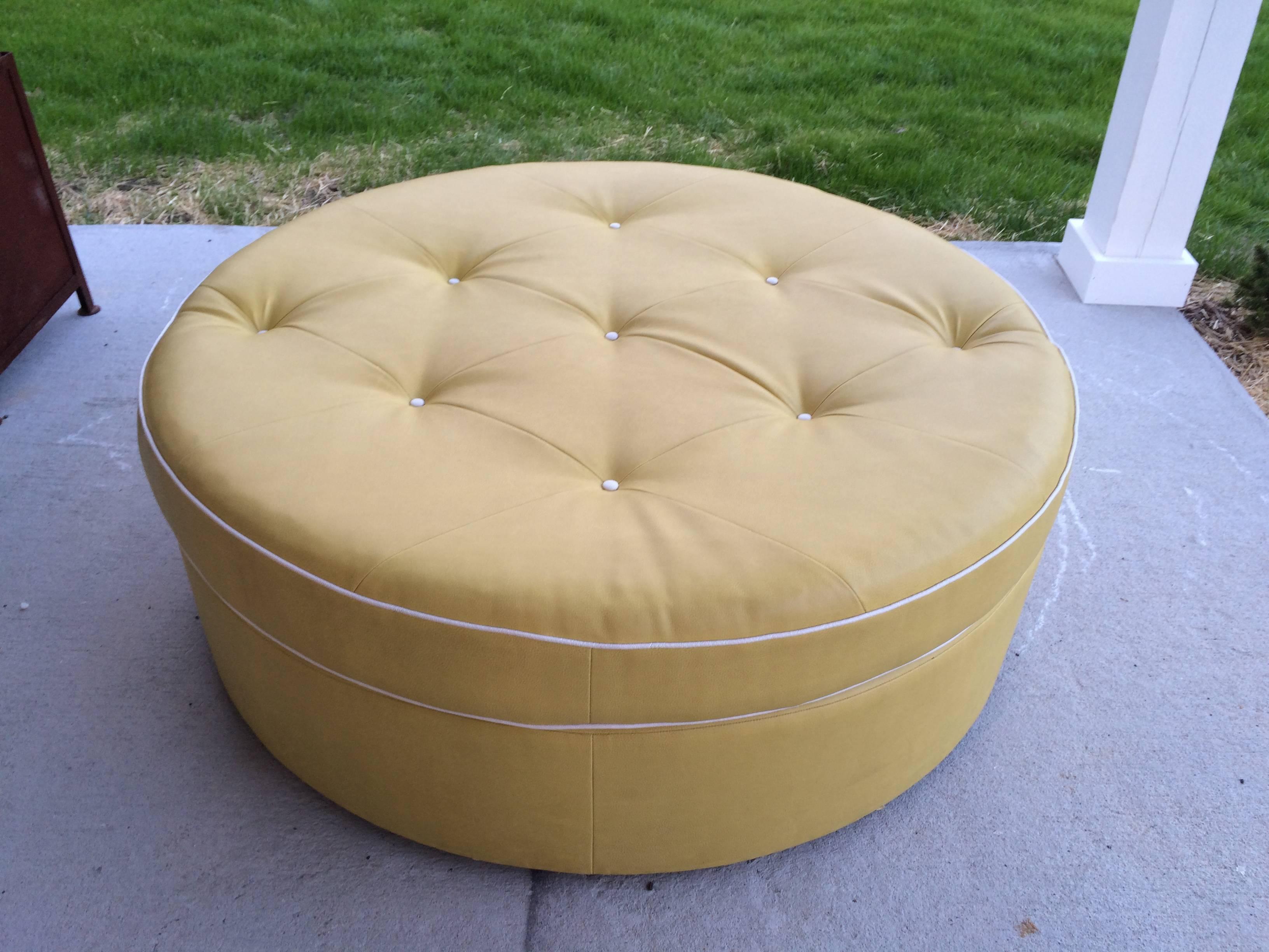 Tufted Round Yellow Ottoman. White buttons and piping against a yellow background. This item is on large brass casters so it is easy to move around. 
Great for dressing room or kids room. Or perfect classy bed for your pet.
Very Hollywood Glam.
