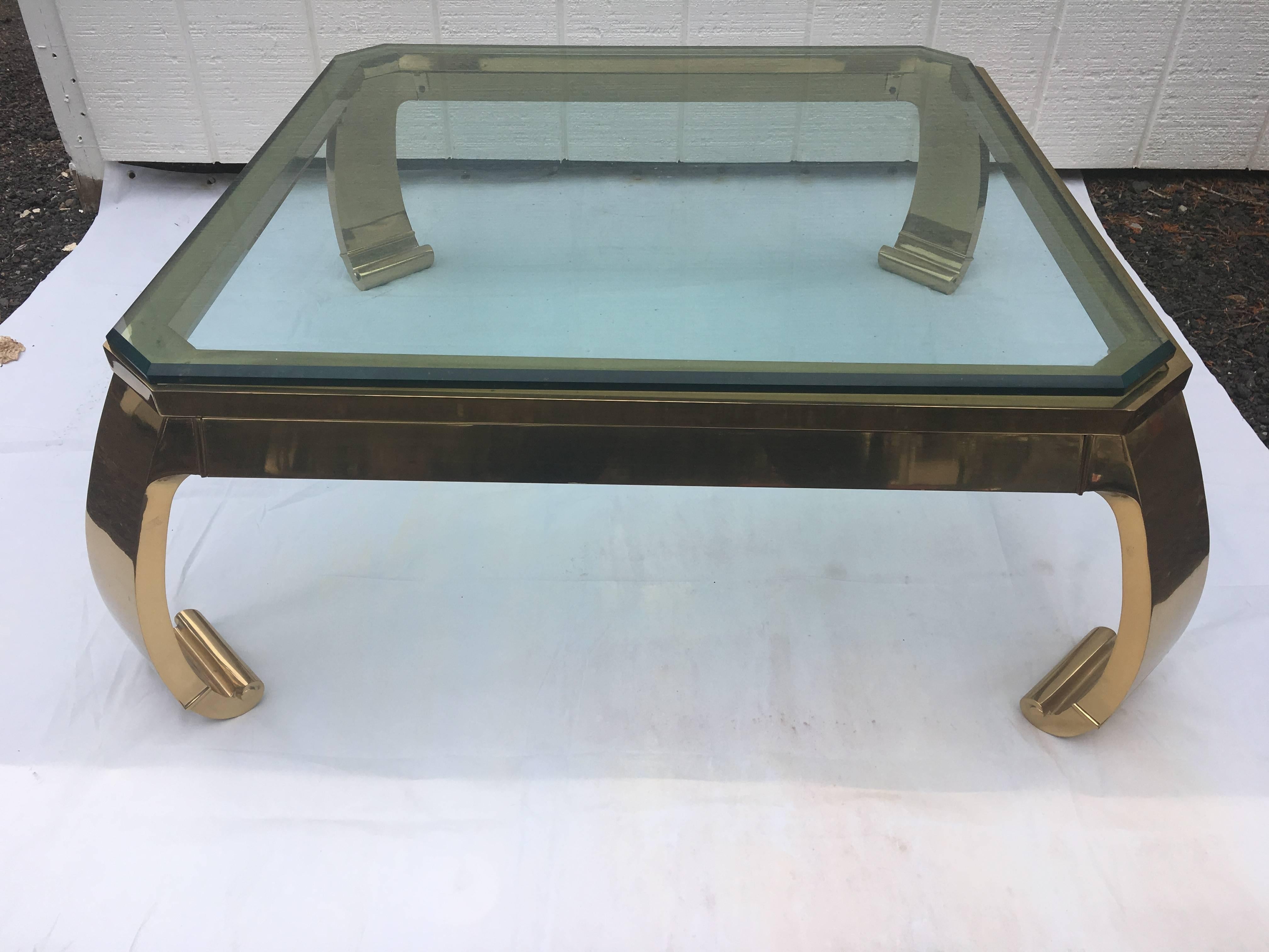 Asian inspired brass coffee table. This classic beauty is made of solid forged brass. It is the epitome of 1970s sexy chic. The 3/4 inch beveled glass top sits on top of the base, unattached. The thick curved Ming style legs on this piece are
