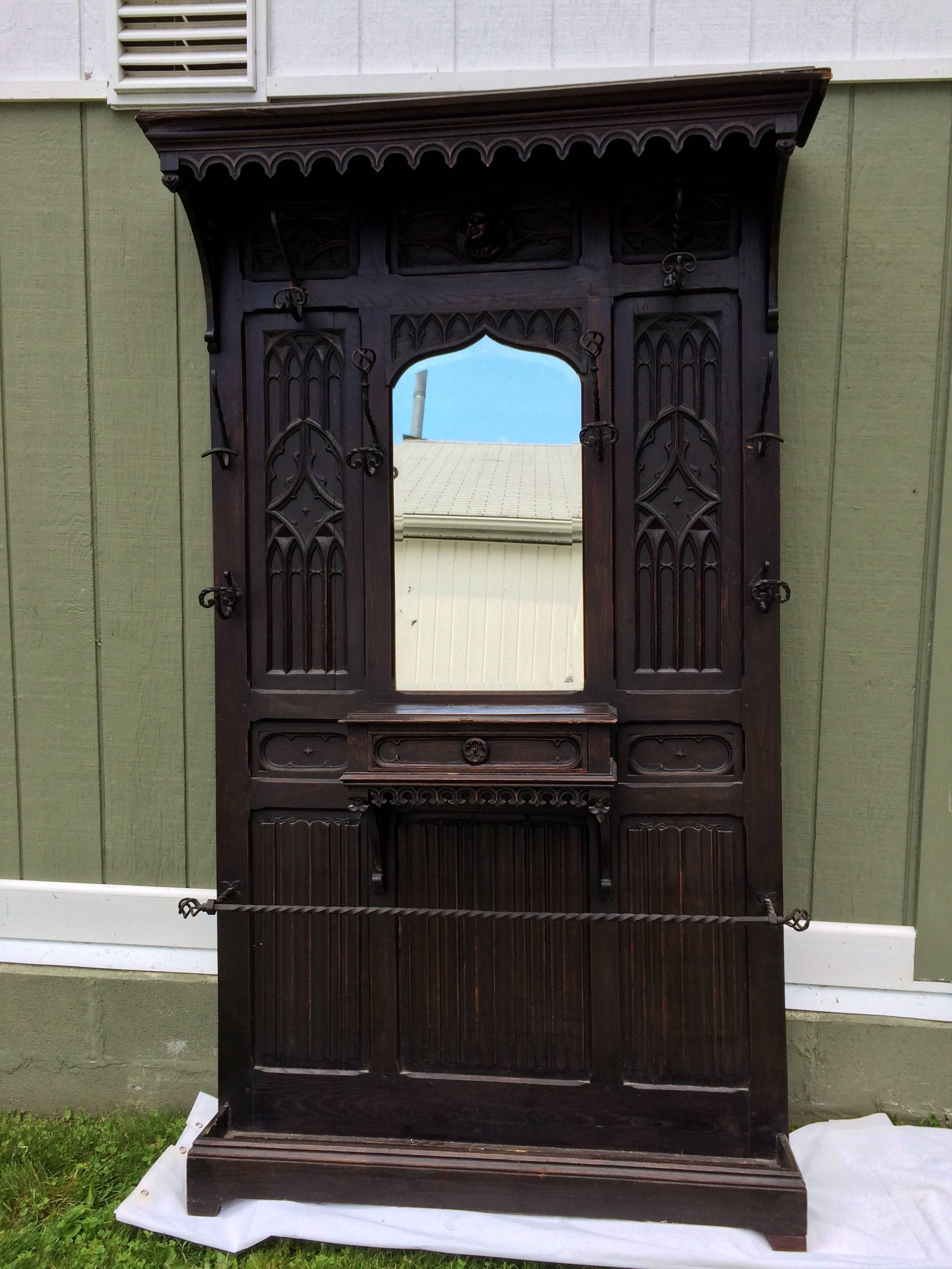 Antique Gothic carved walnut hall tree. One of a kind ornate, heavily carved piece with attention to detail. hand-wrought iron hooks adorn this majestic beauty. Single carved drawer for gloves or keys. lower area for umbrellas. Missing the inner