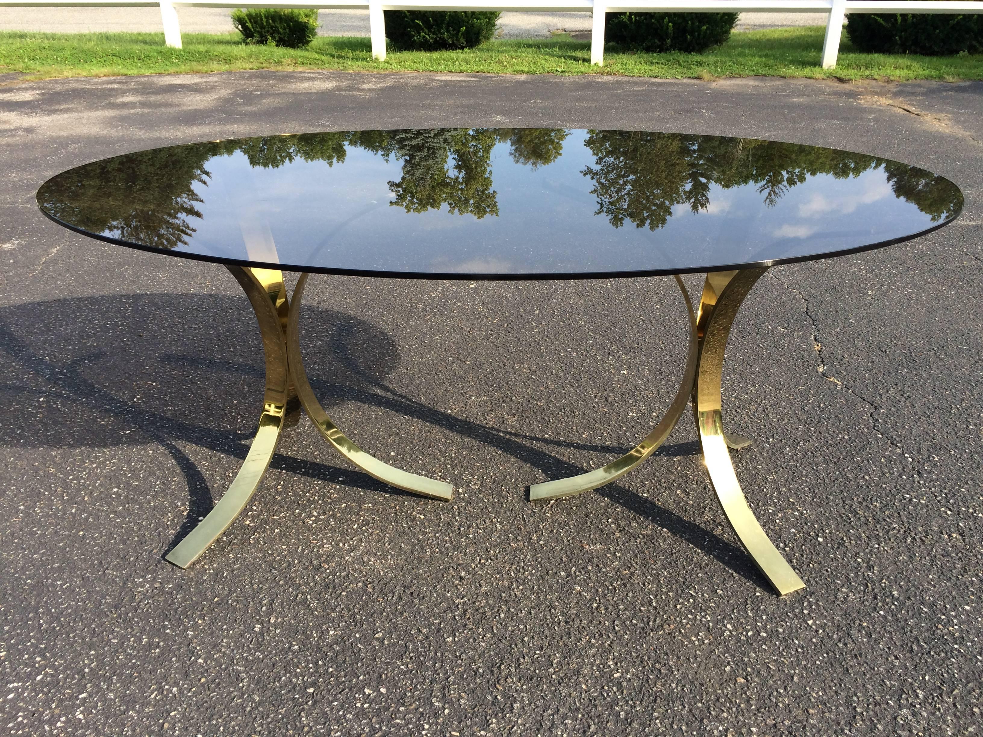Roger Sprunger Brass and Smoked Glass Oval Dining Table. The glass is separate from the two heavy , solid brass double pedestal bases. It could possibly be a Mastercraft piece as well. No signature found.  Very elegant and sleek. Scratches to brass