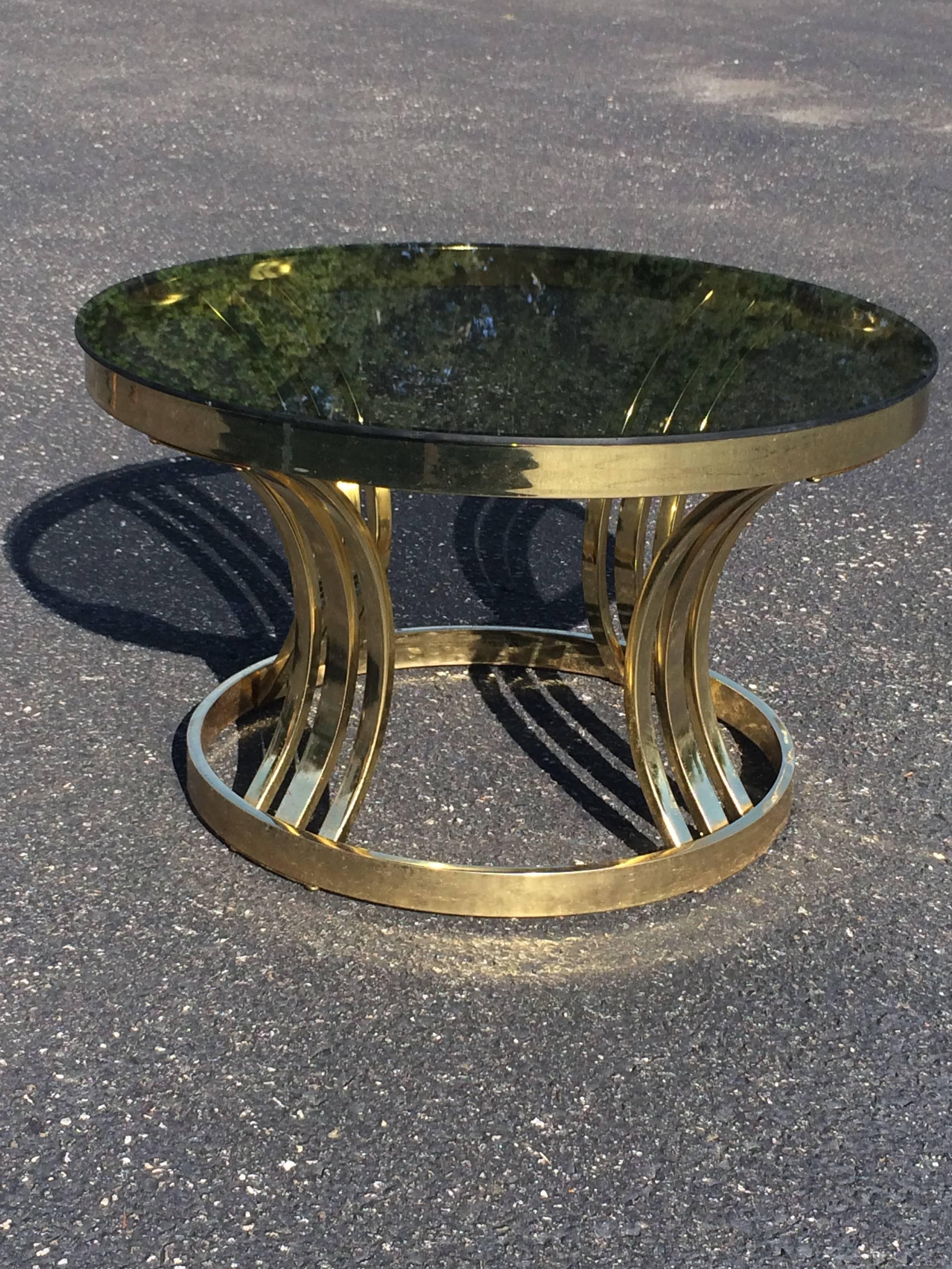 Mid-Century brass and smoked glass round coffee table by Milo Baughman. Nice size to this sleek table. Some wear to brass plating and some wear to glass top but overall a fabulous table. It can also be used as a side table due to its size. Glass is
