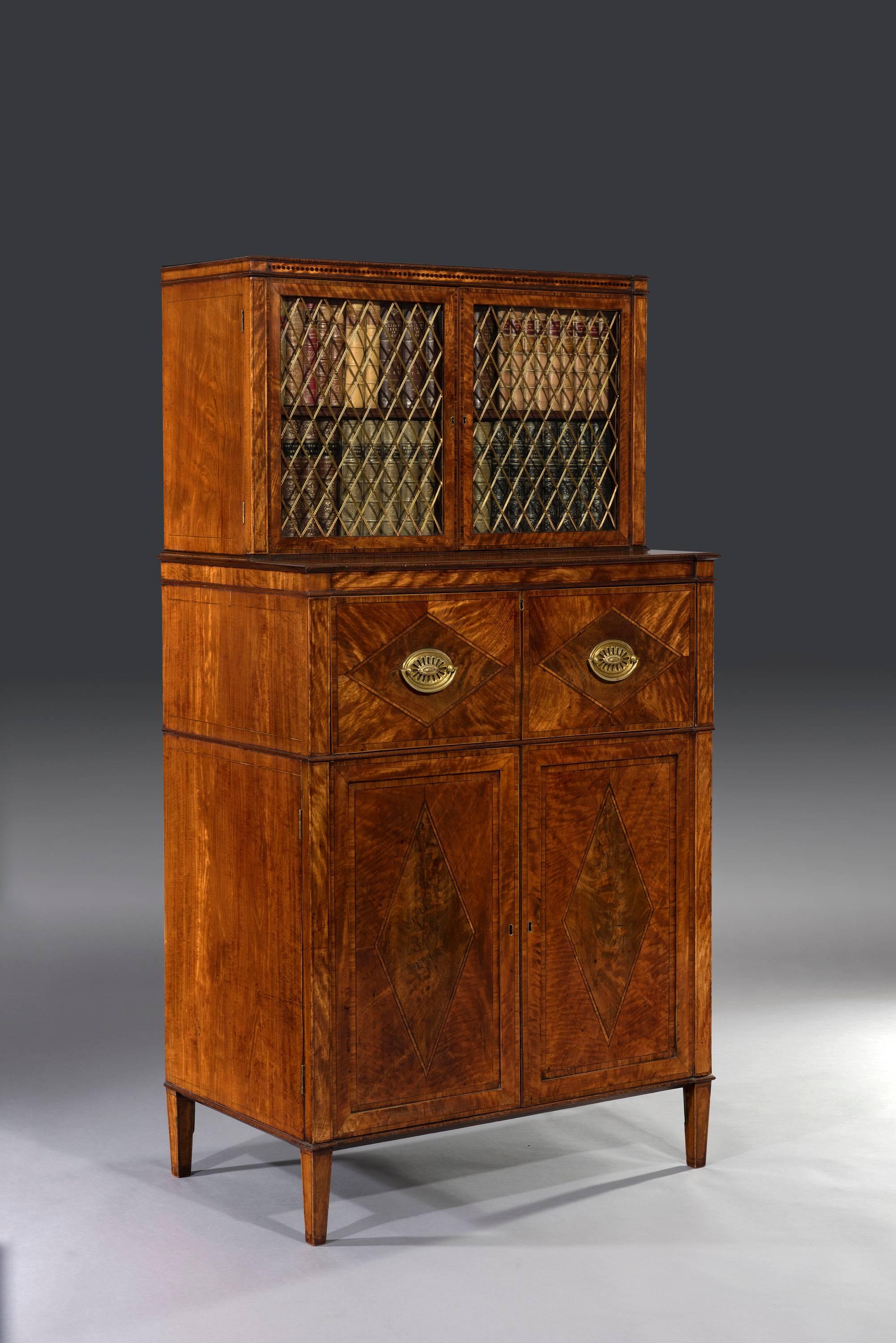George III Sheraton period 18th century satinwood inlaid secrétaire dwarf bookcase. 

The inlaid and crossbanded satinwood two-door bookcase above a secrétaire chest is fitted with lozenge-shaped gilt-brass grills, glass panels and a mahogany