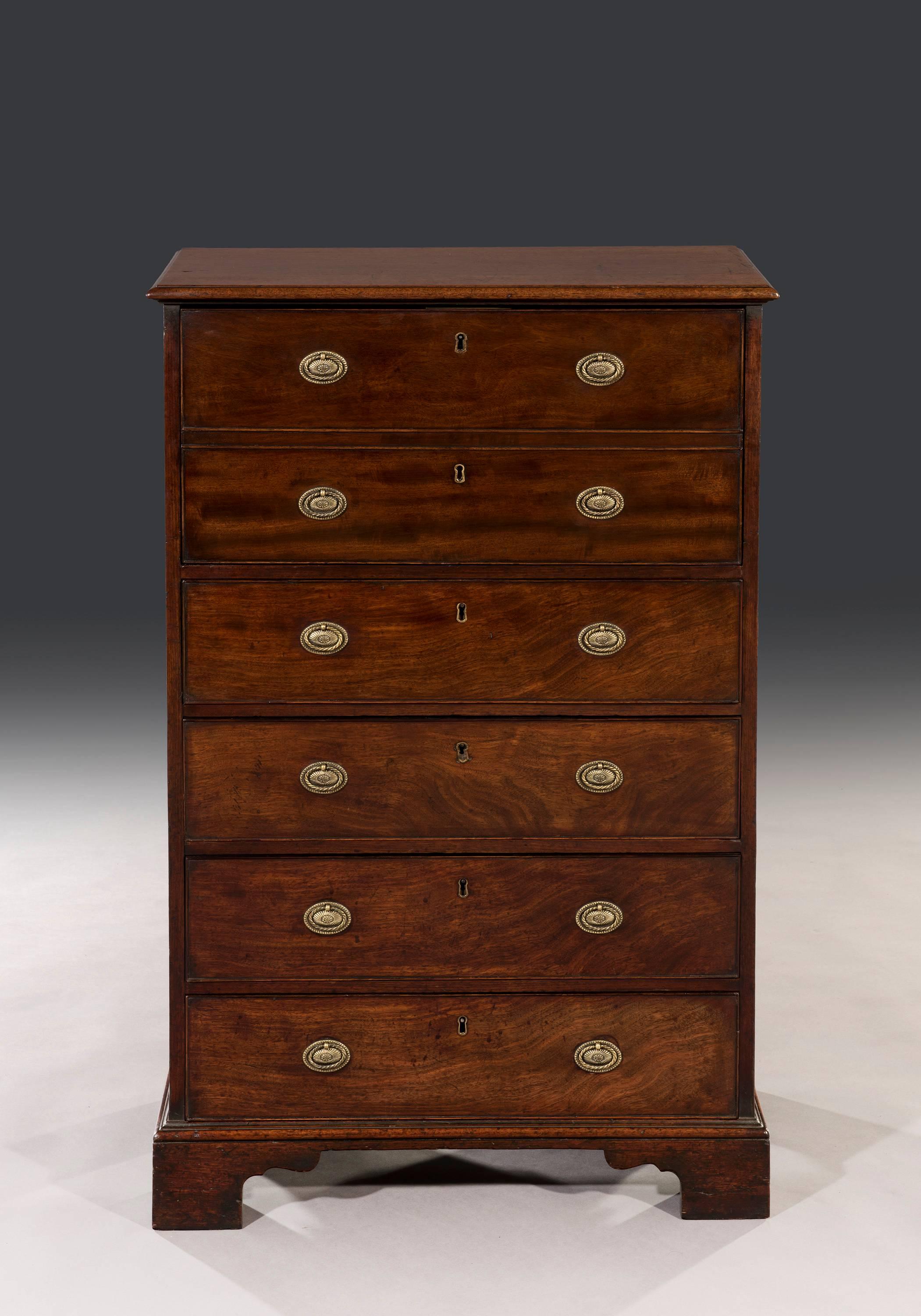 The rectangular mahogany moulded top sits above highly figured side panels and the chest has a concealed secrétaire drawer and four mahogany drawers fitted with later replaced handles. The secrétaire chest stands on its original ogee bracket feet.