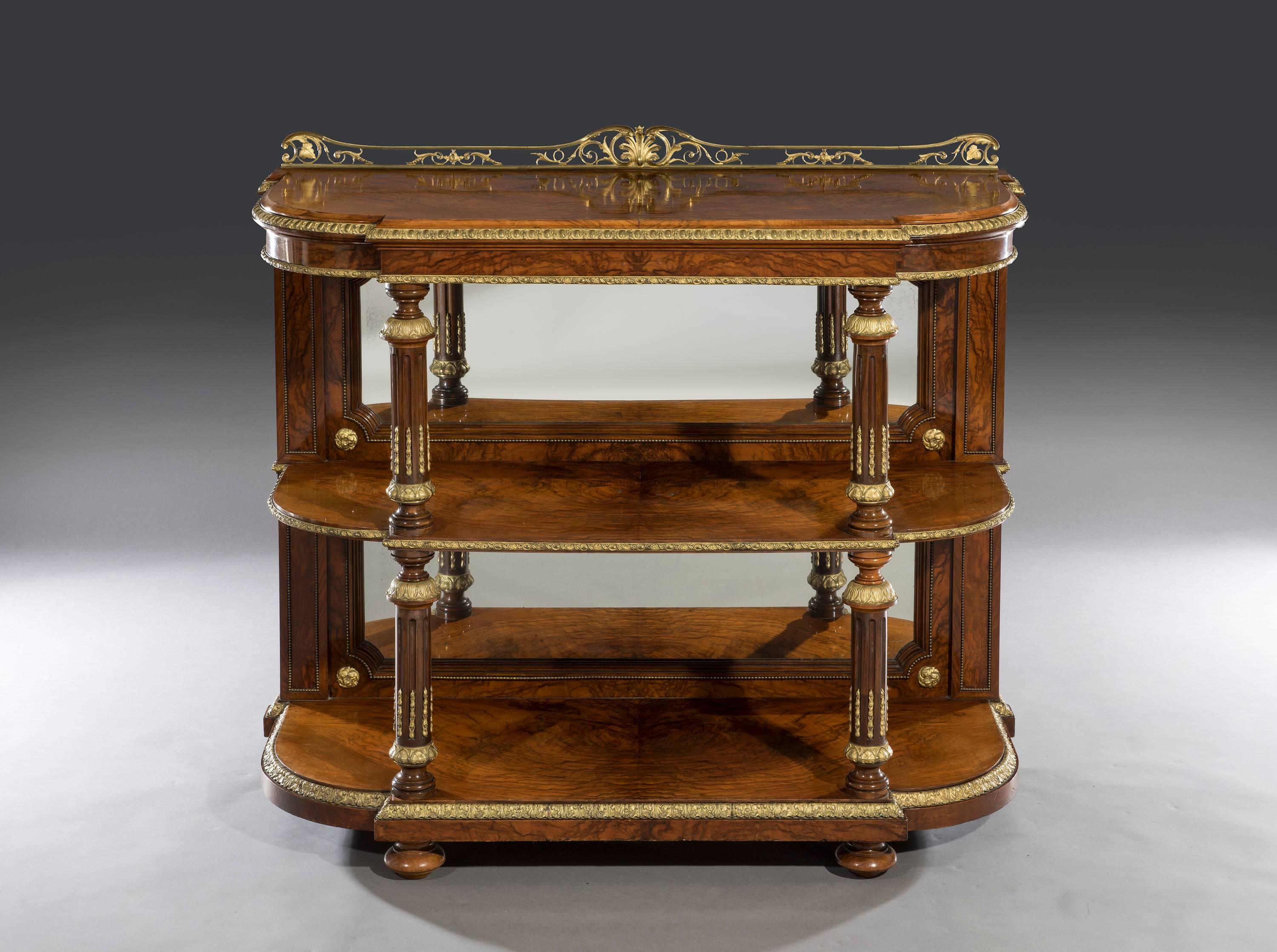 The burr walnut breakfront top with a bevelled edge is fitted with a highly decorative shaped gallery above a burr walnut veneered frieze. The inset mirrored backs are surmounted on shaped walnut and brass beaded mouldings with gilt-metal mounts to